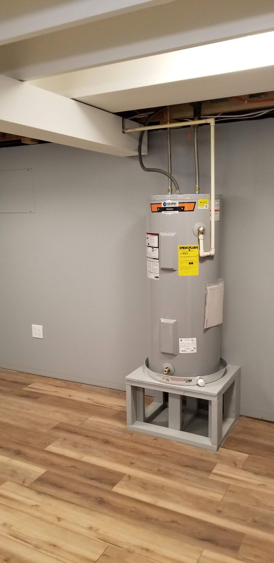 A water heater is sitting on top of a wooden floor in a room.