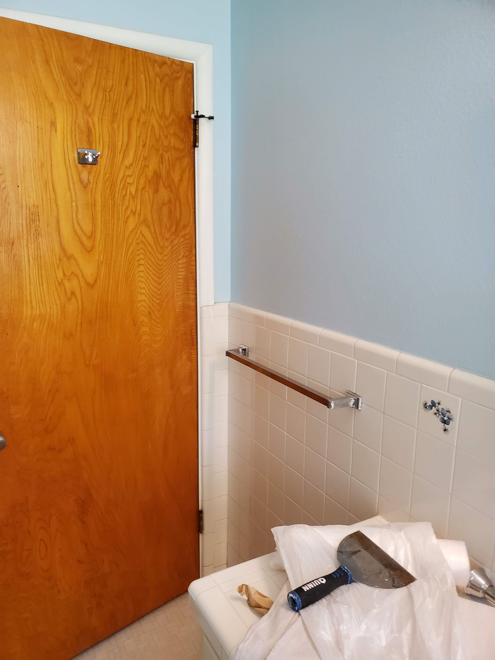 A bathroom with a wooden door and white tiles
