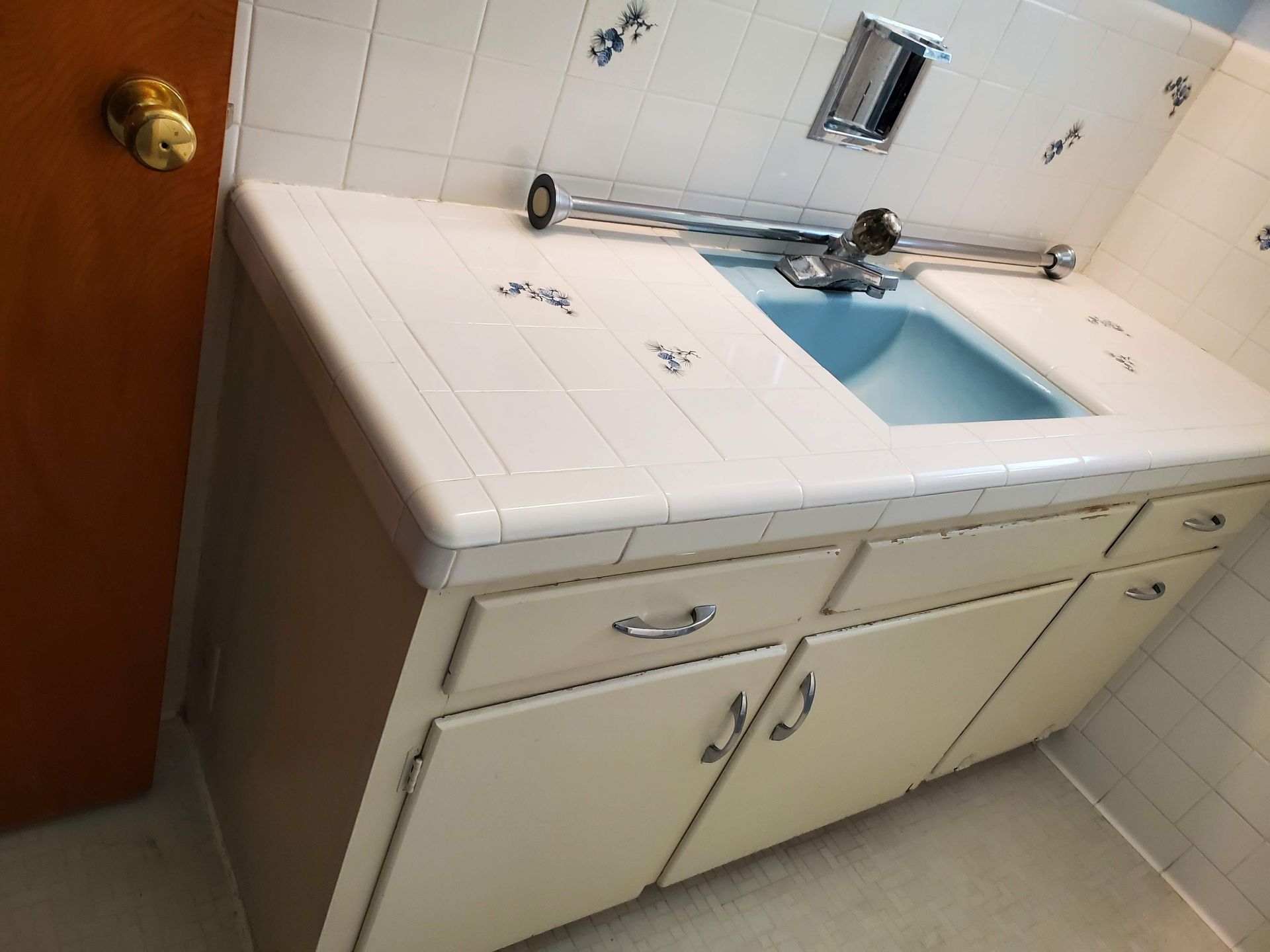 A bathroom with white cabinets and a blue sink