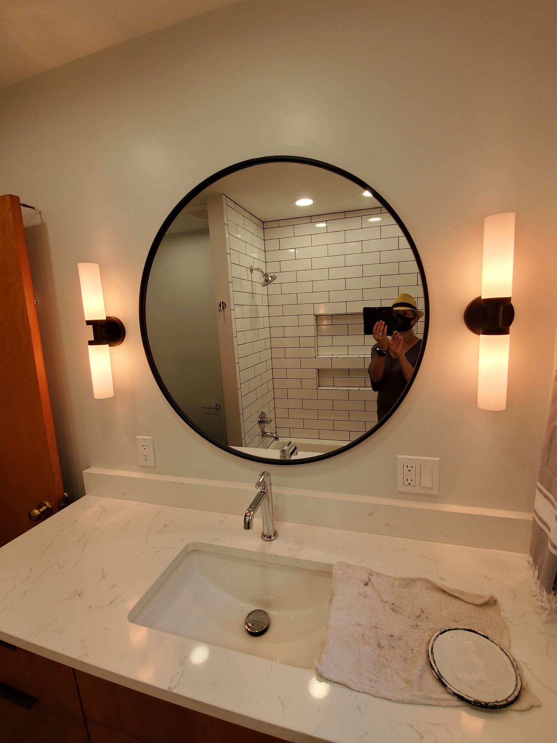 A bathroom with a round mirror and a sink