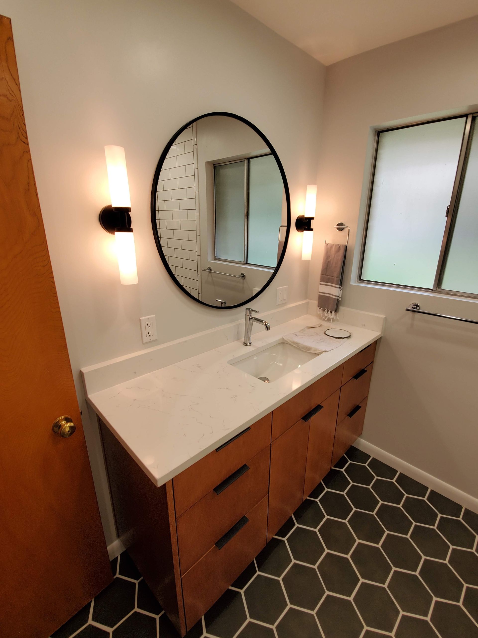 A bathroom with a sink and a round mirror