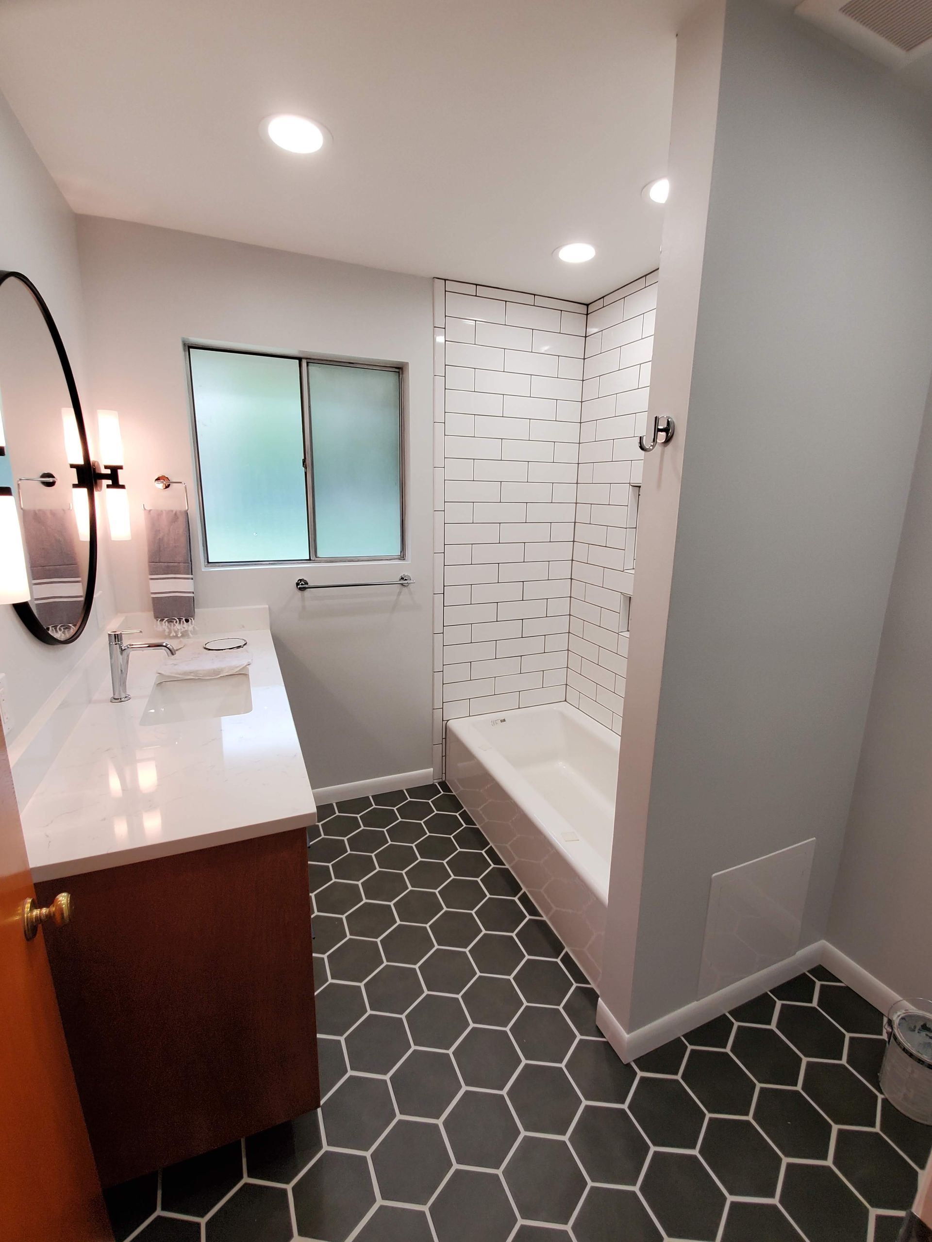 A bathroom with a tub , sink , mirror and shower.