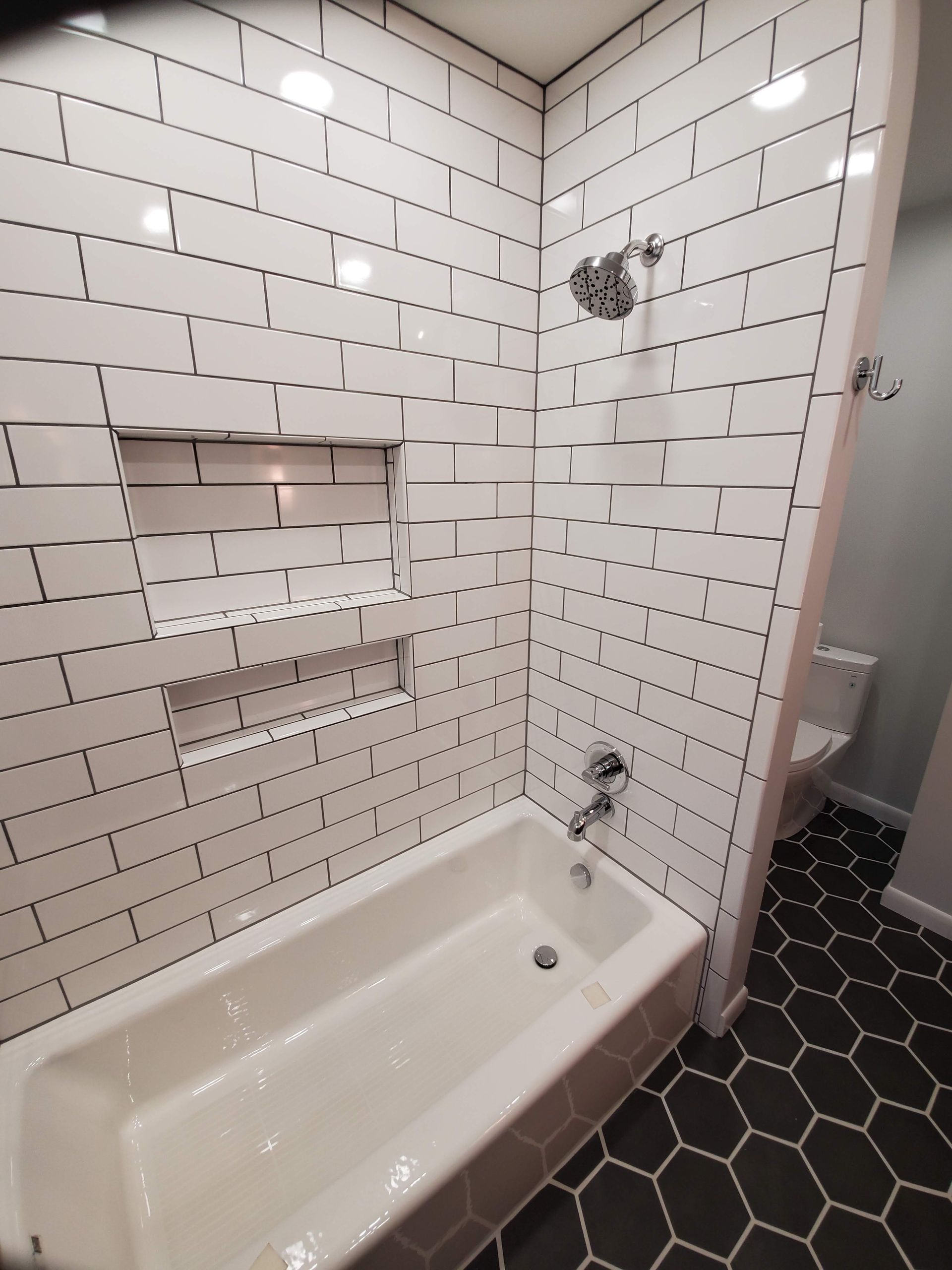 A bathroom with white tiles and a bathtub