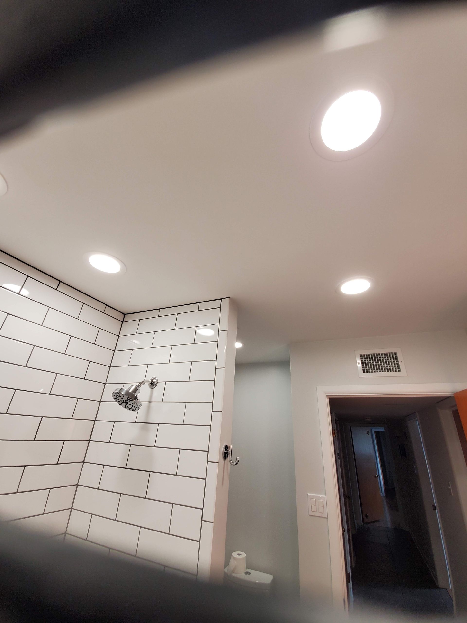 A bathroom with white tiles and a light on the ceiling