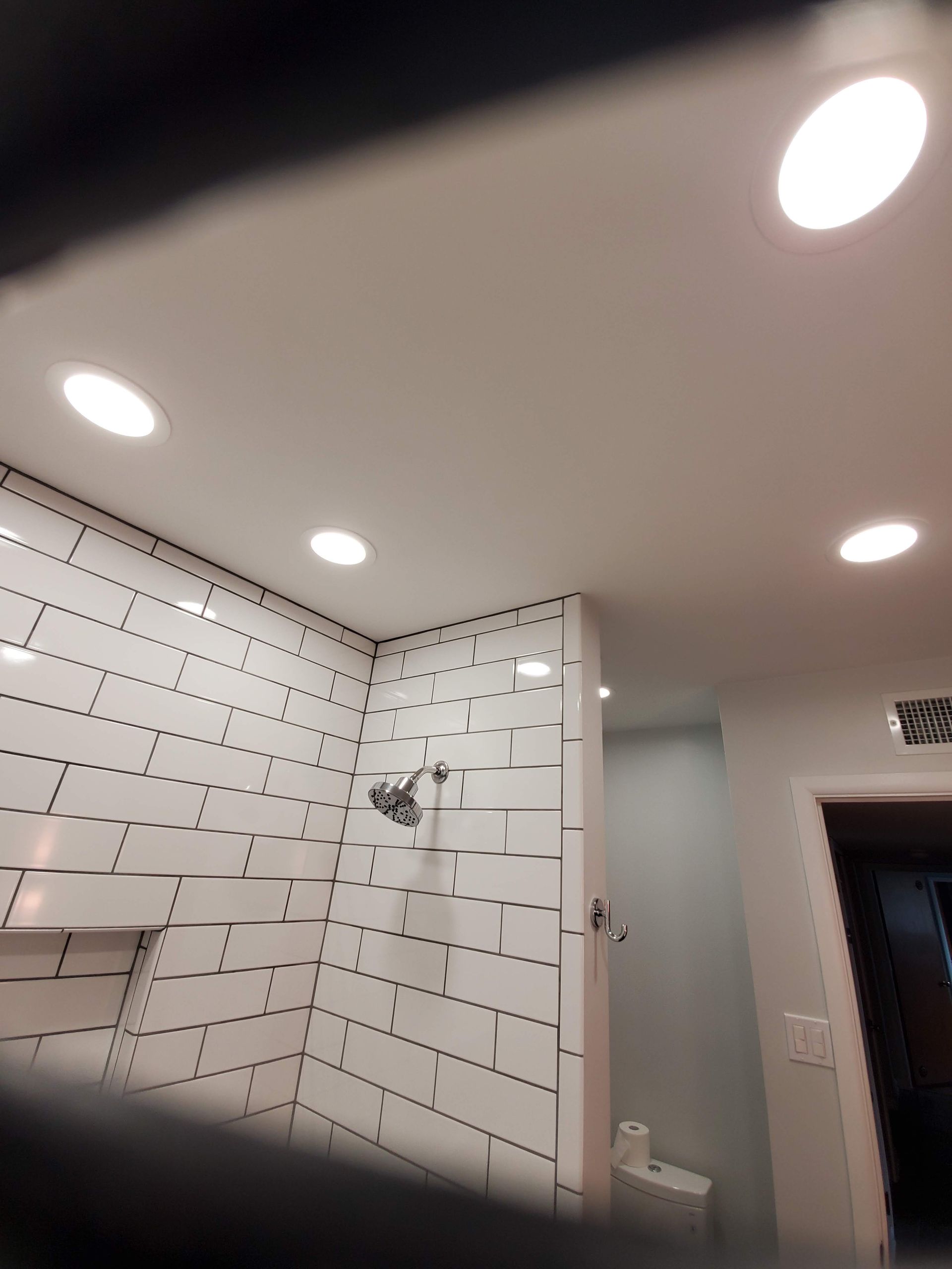 A bathroom with white tiles and a shower head