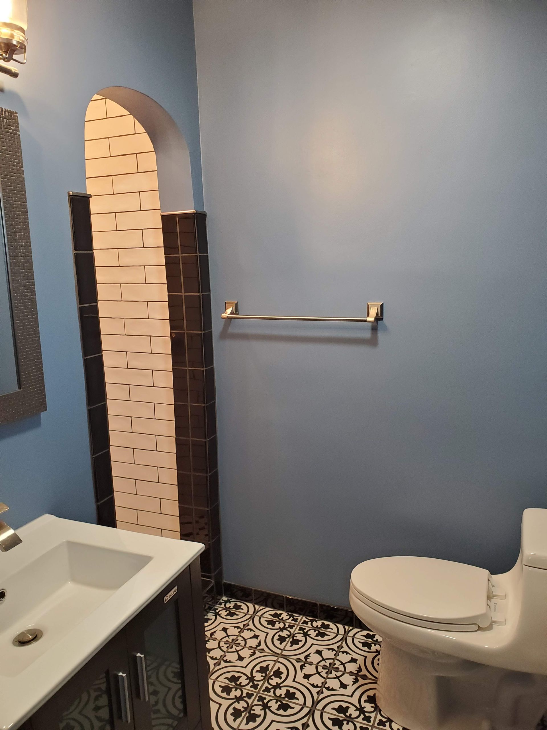 A bathroom with a toilet , sink and mirror.