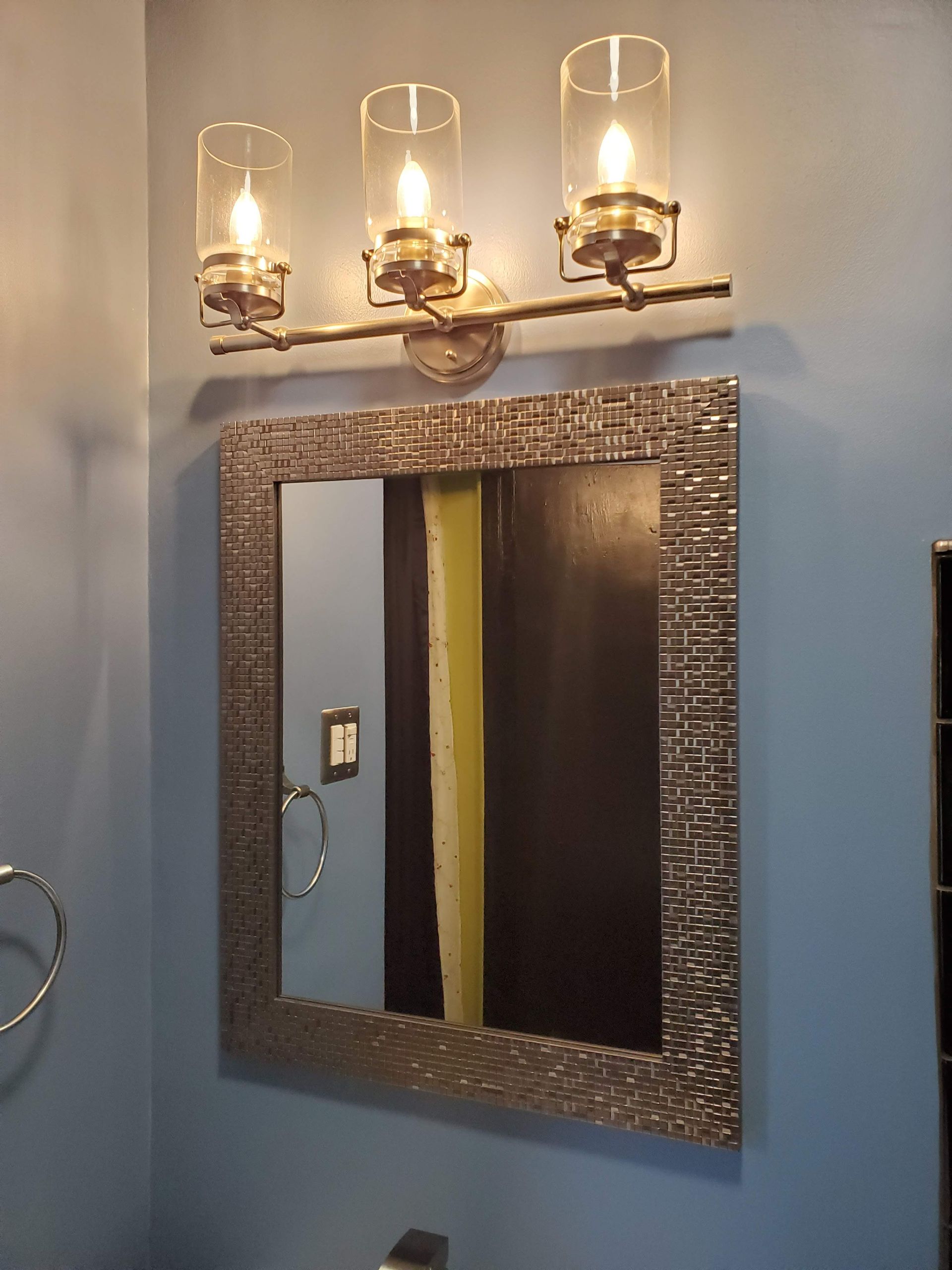 A bathroom mirror with three lights above it