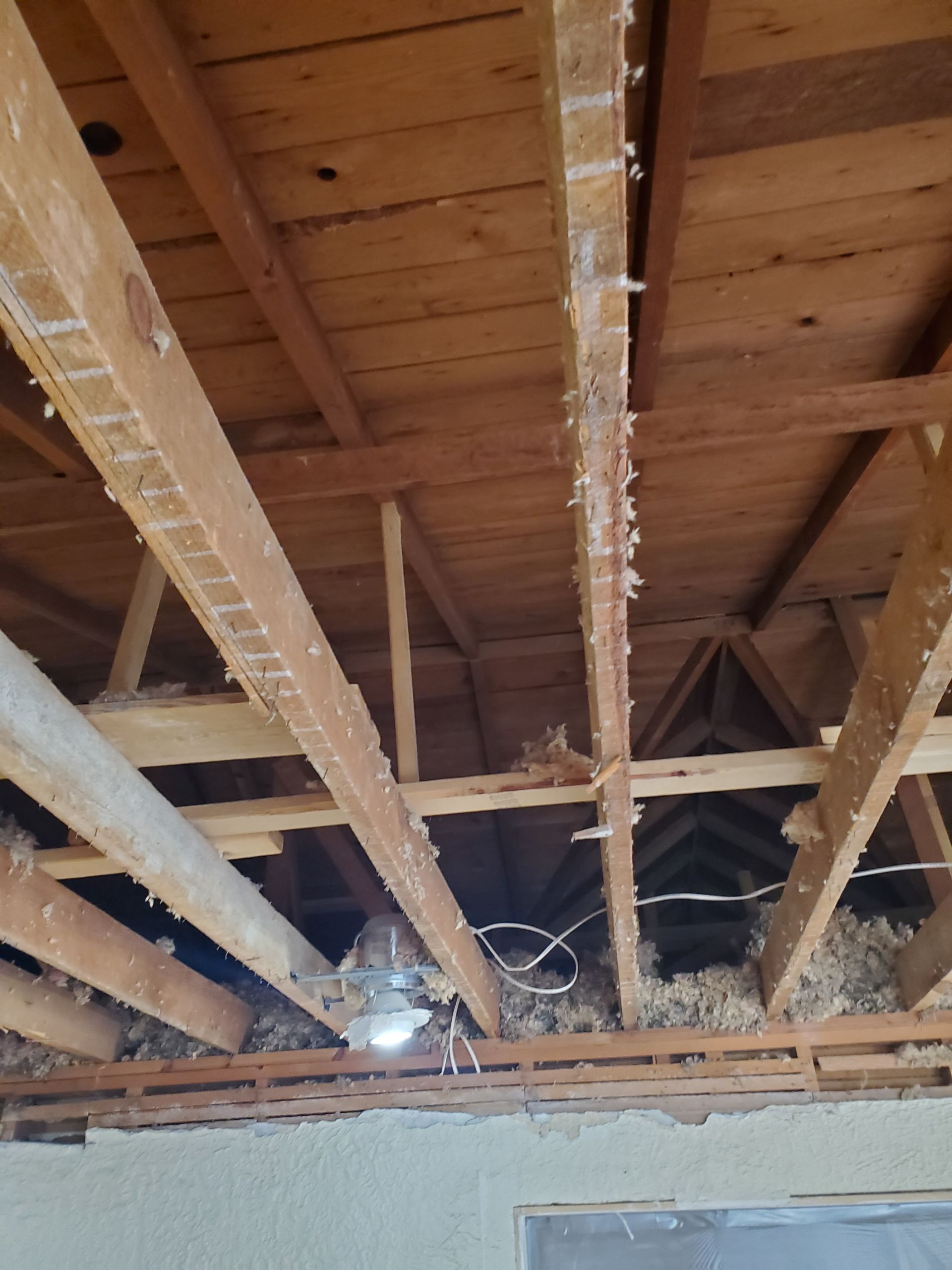 The ceiling of a house with wooden beams and a ceiling fan.