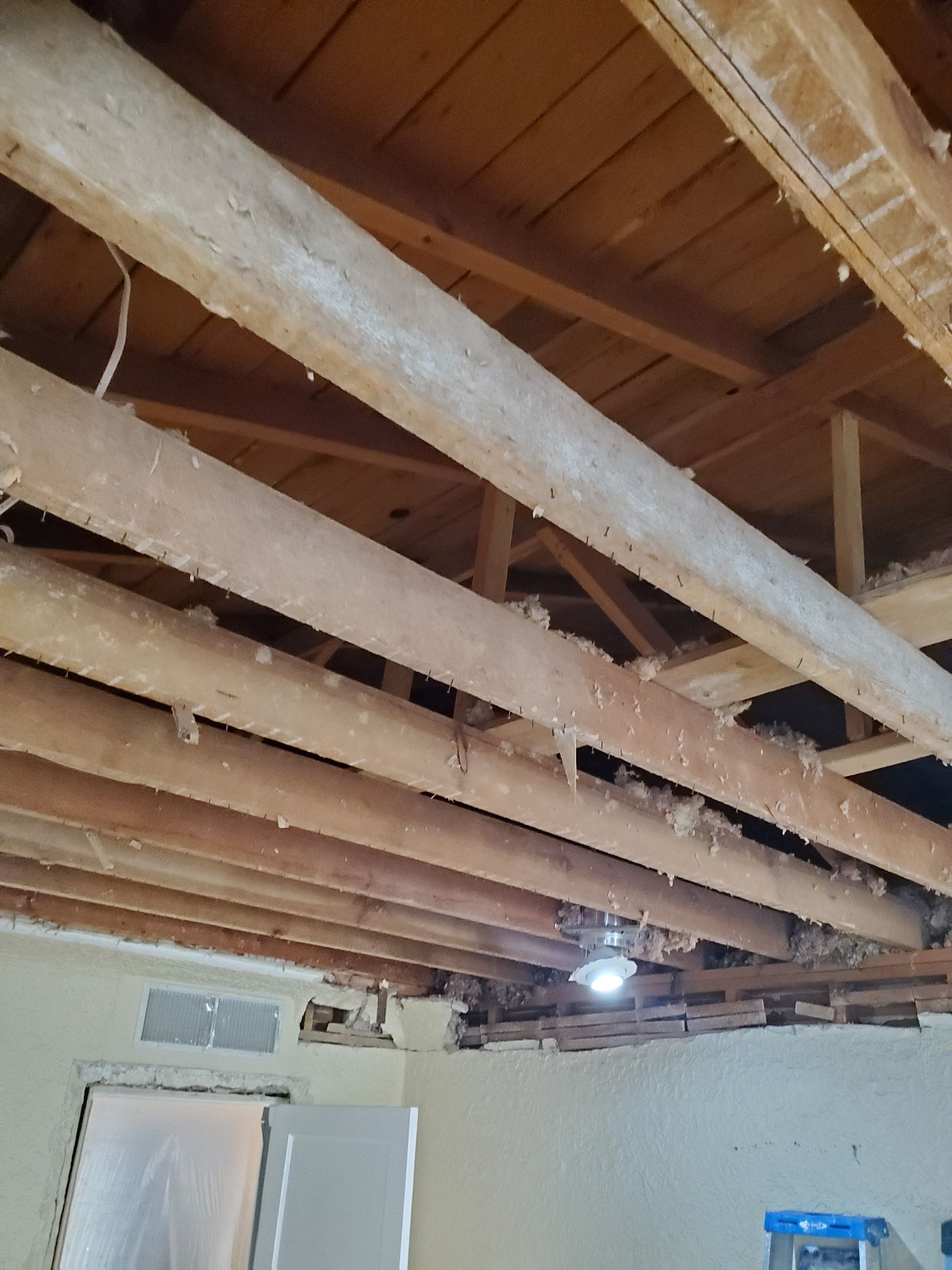 A ceiling with a lot of wooden beams and pipes