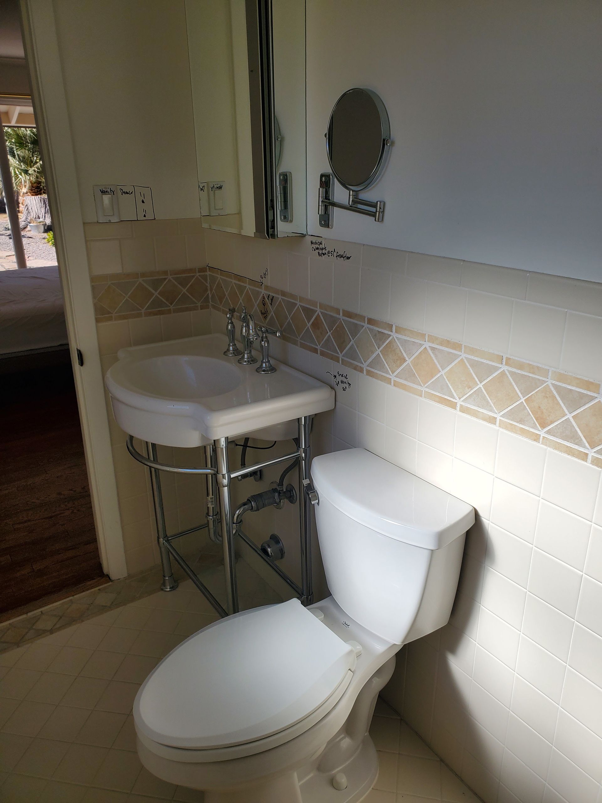 A bathroom with a toilet , sink and mirror.