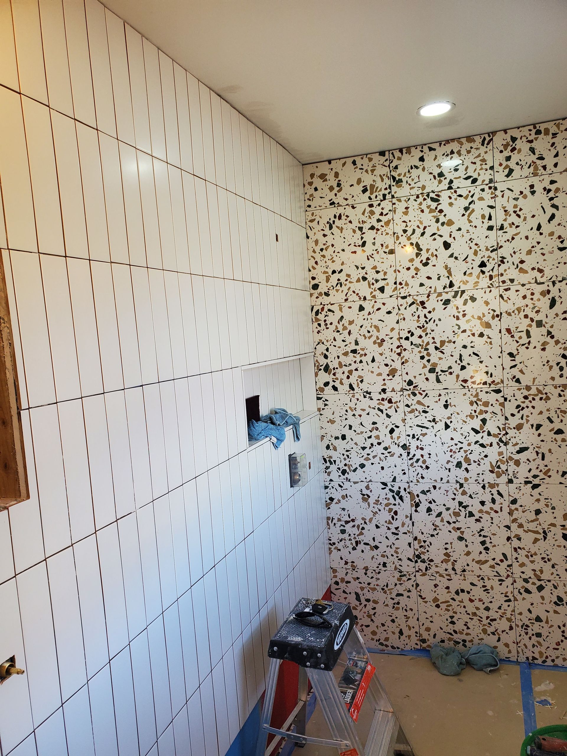 A room with a lot of tiles on the wall and a ladder on the floor.