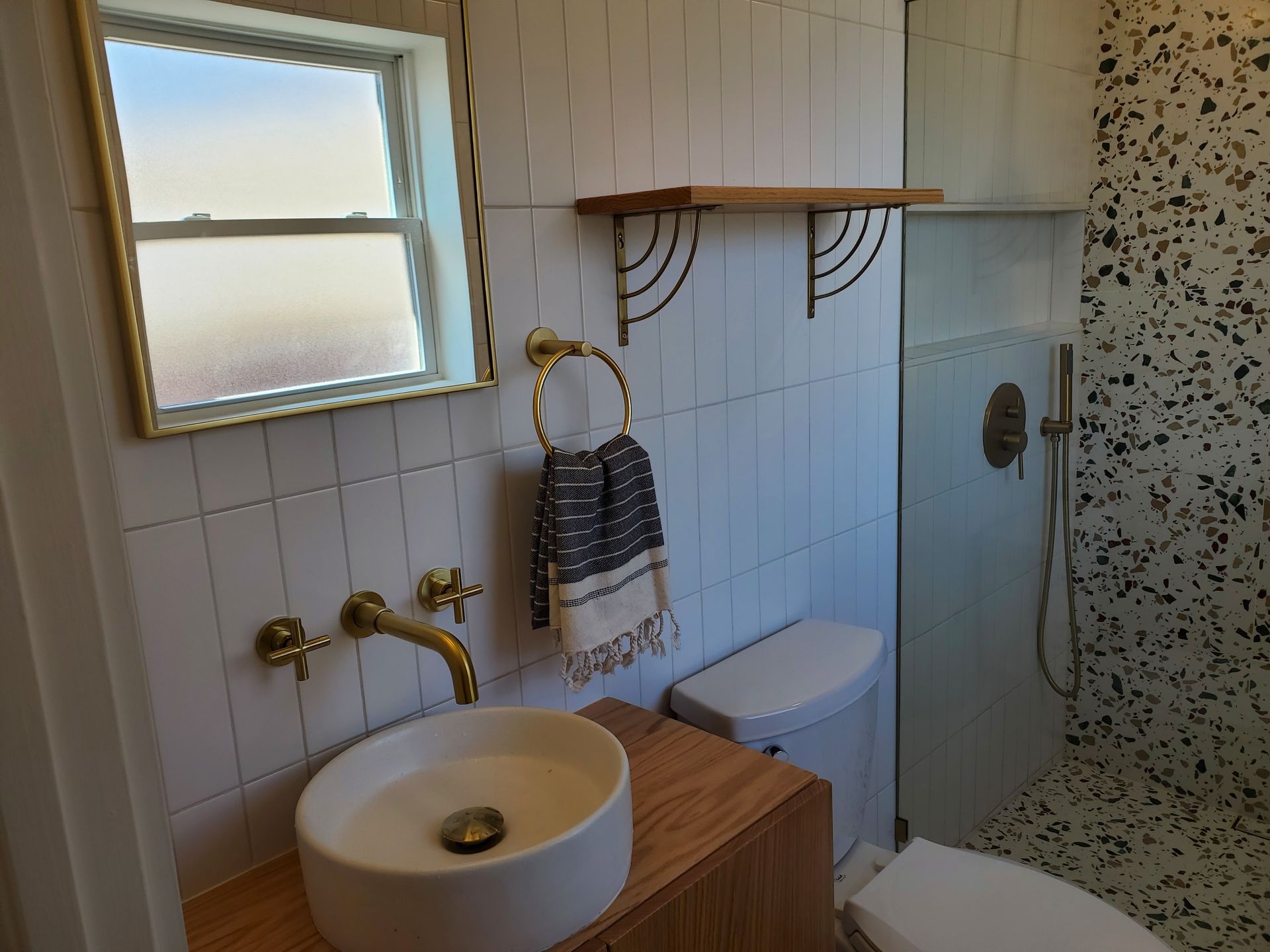 A bathroom with a sink , toilet , mirror and shower.