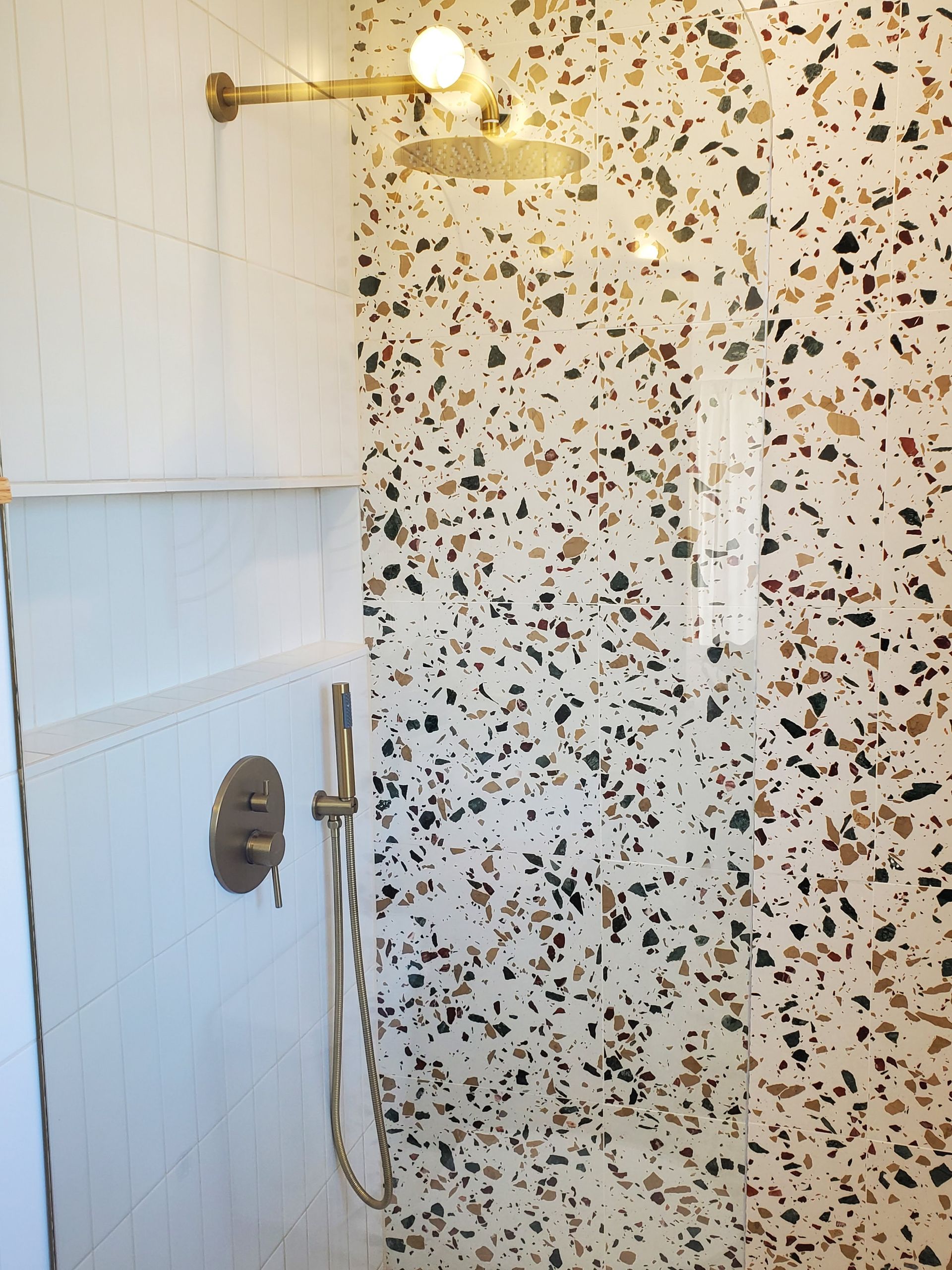 A shower with a shower head and a light on the wall