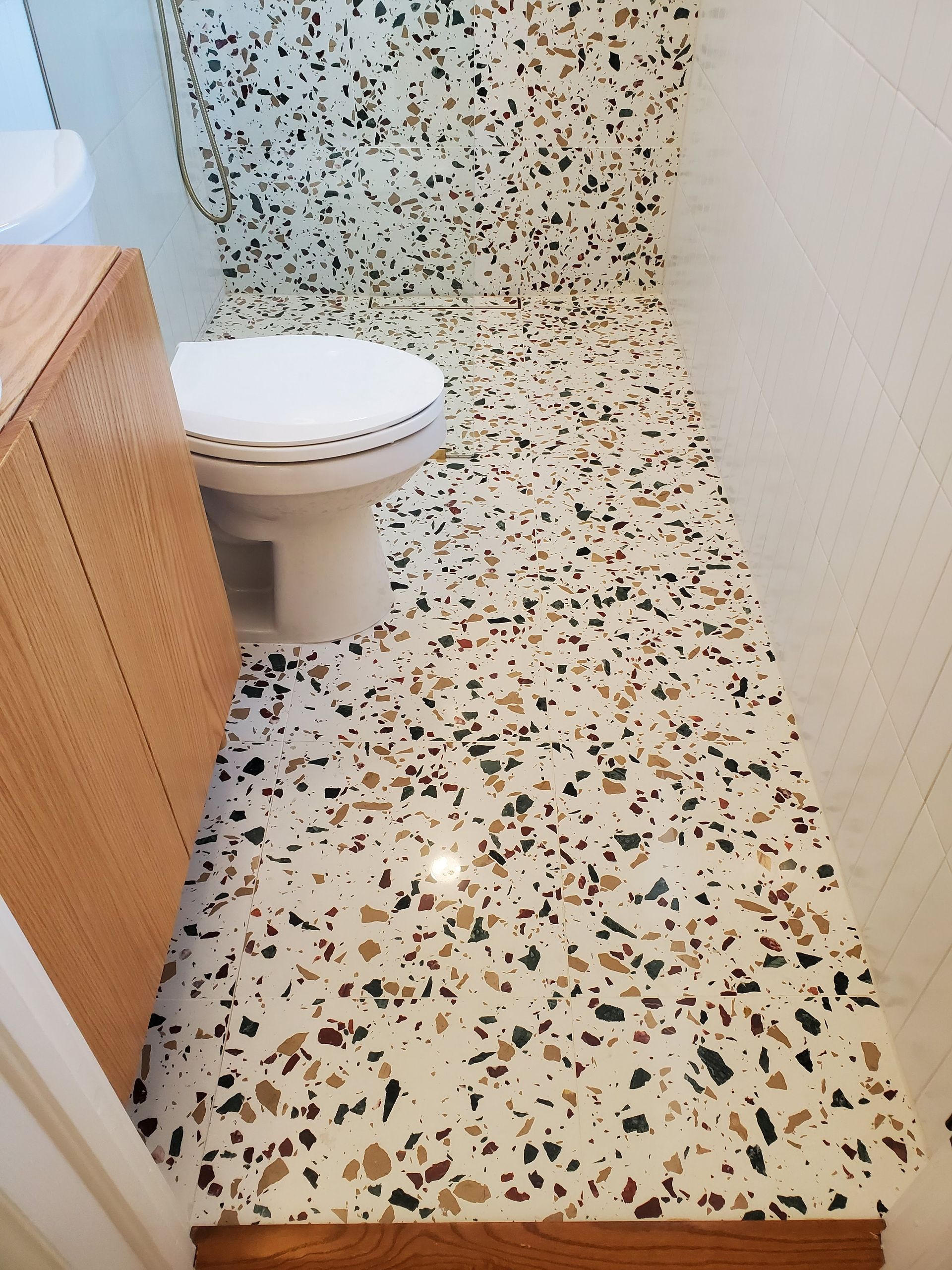 A bathroom with a terrazzo floor and a toilet