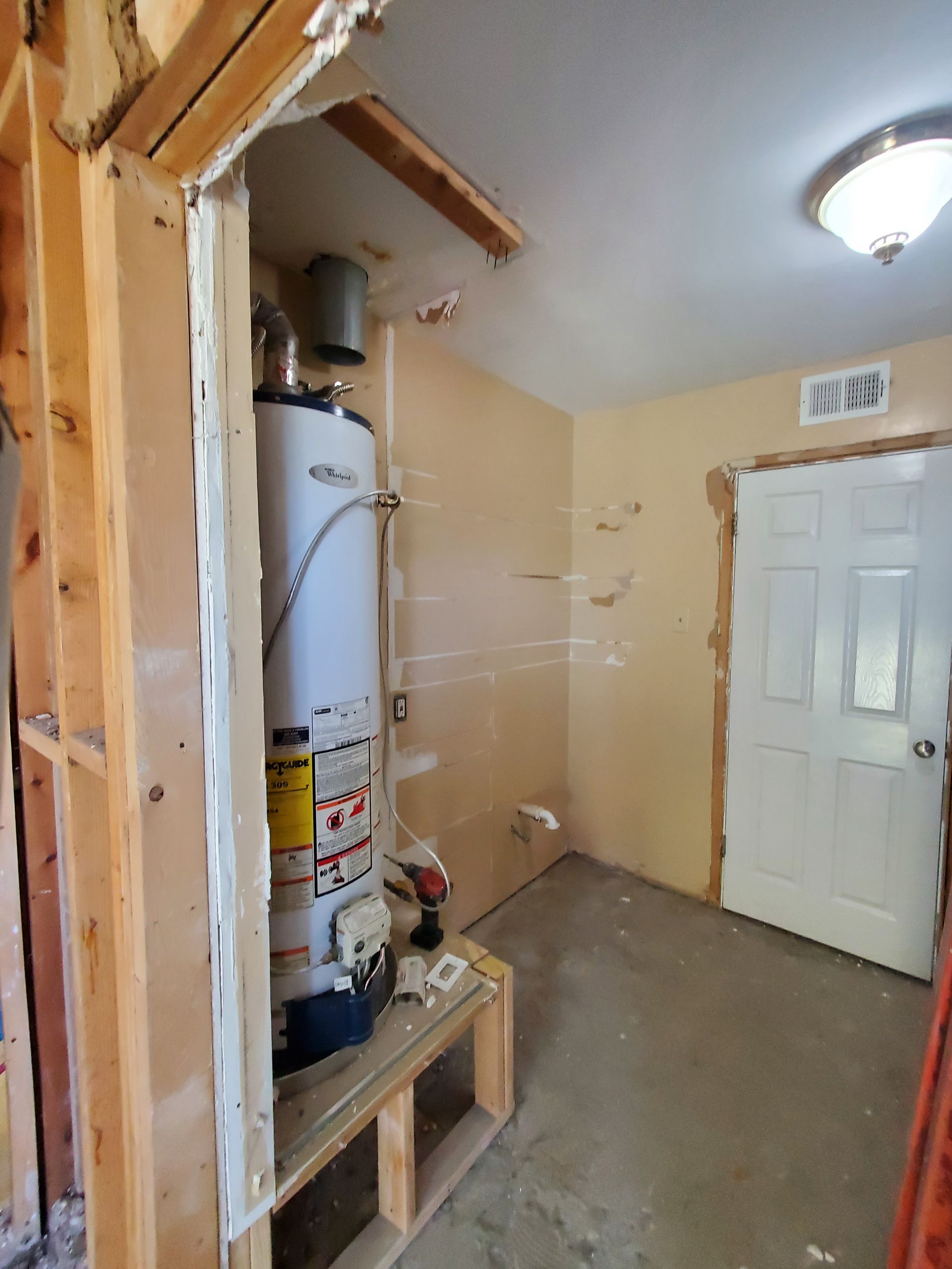 A room with a water heater in it and a door.