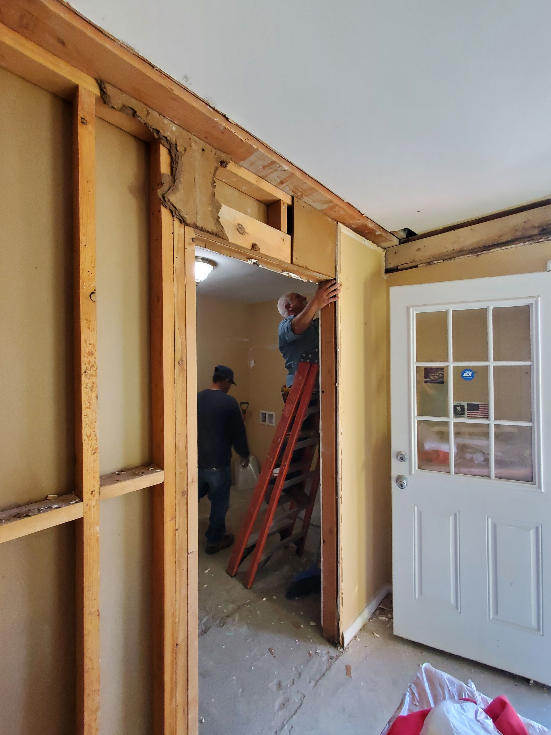 A man standing on a ladder in a room next to a door