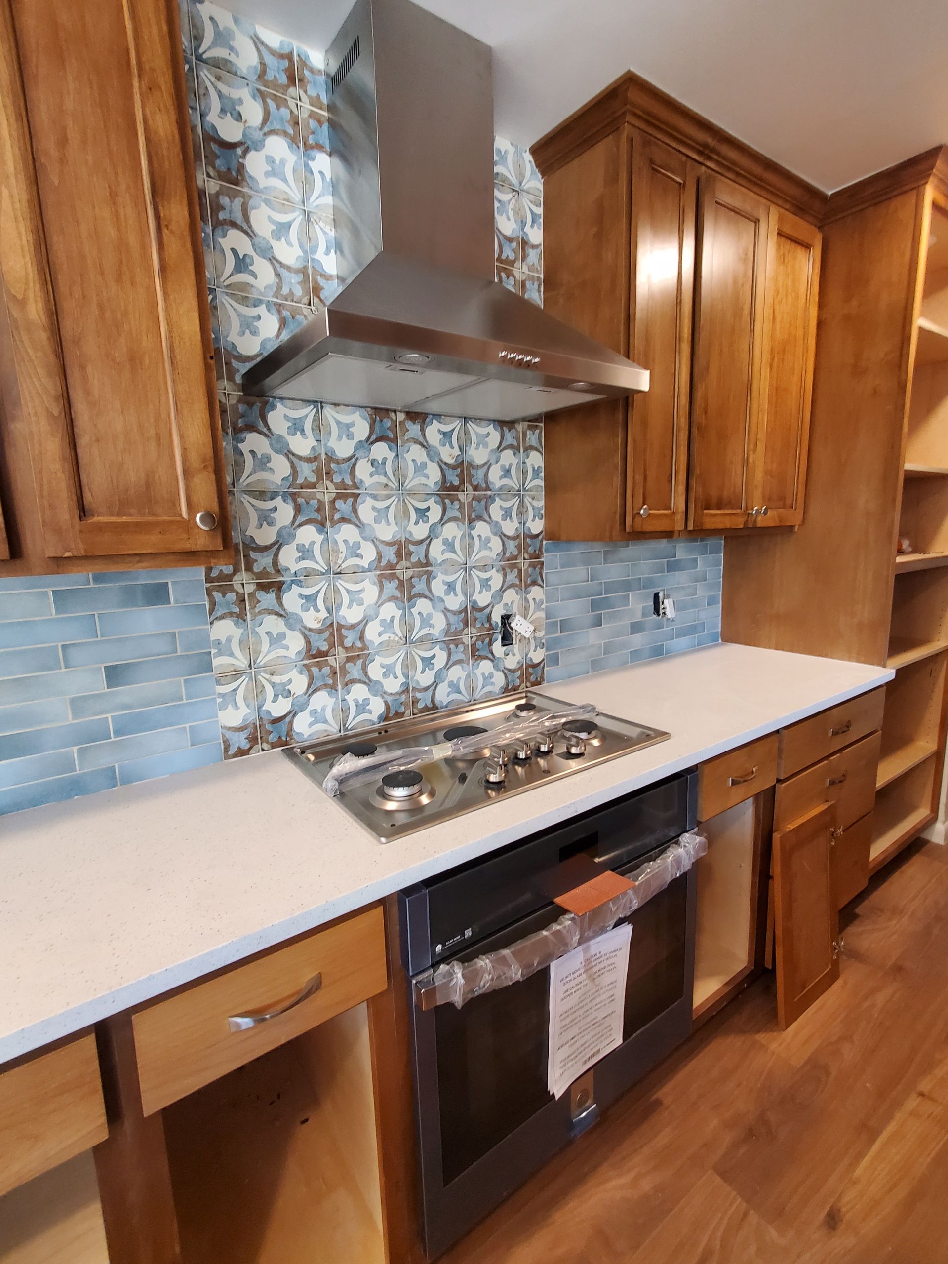 A kitchen with wooden cabinets , a stove , and a hood.