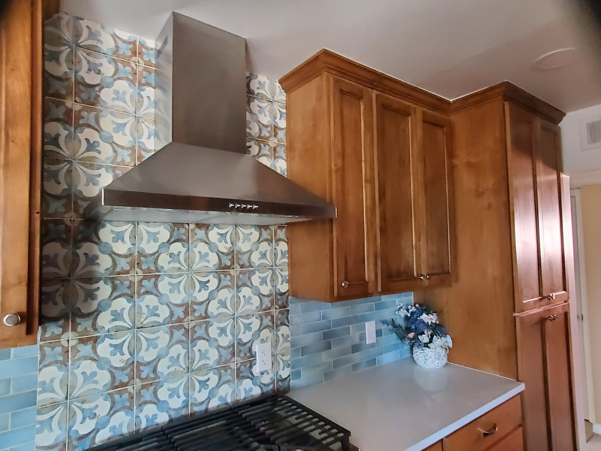 A kitchen with wooden cabinets , a stove , and a hood.