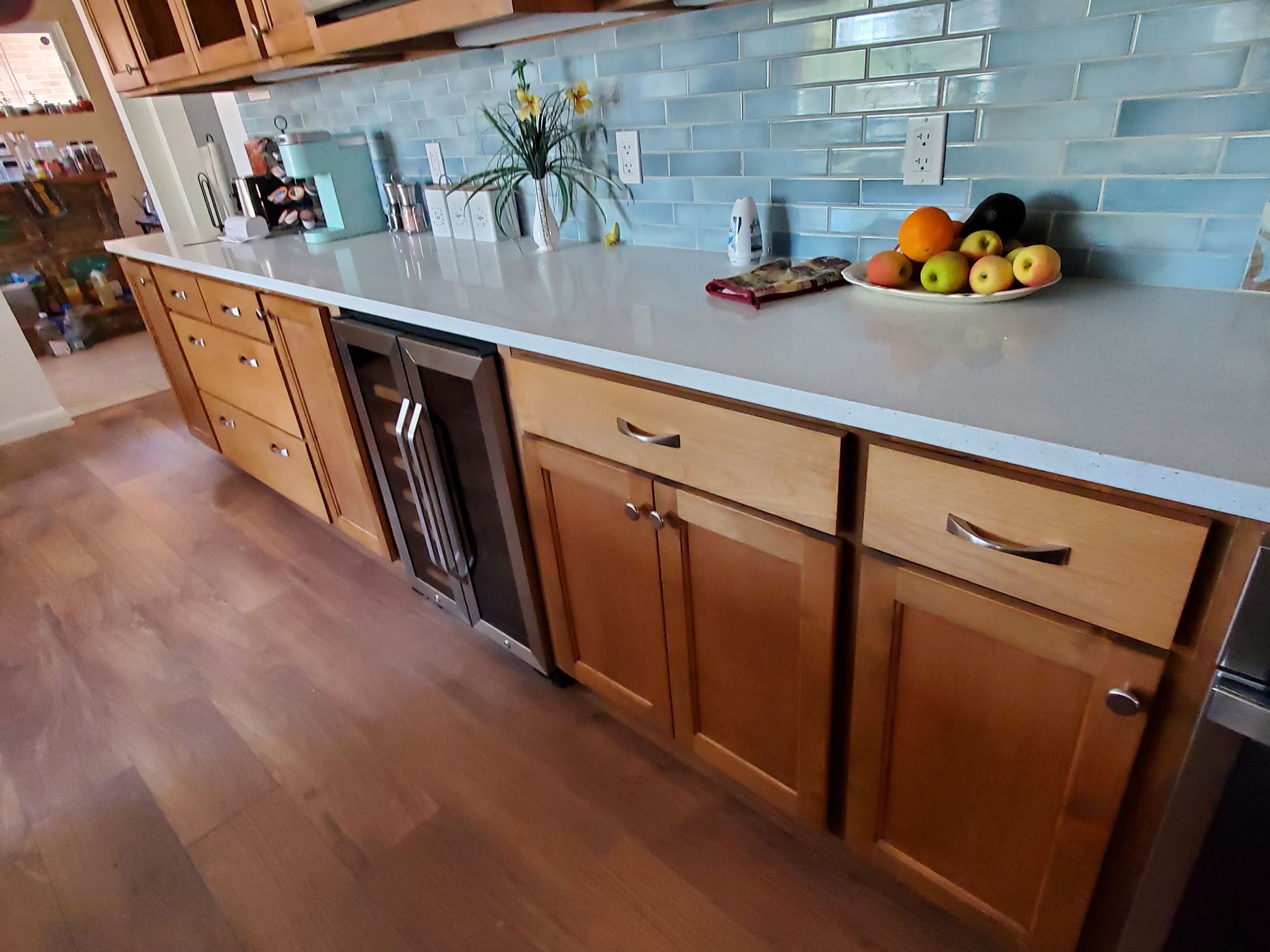 A kitchen with wooden cabinets and stainless steel appliances and a bowl of fruit on the counter.