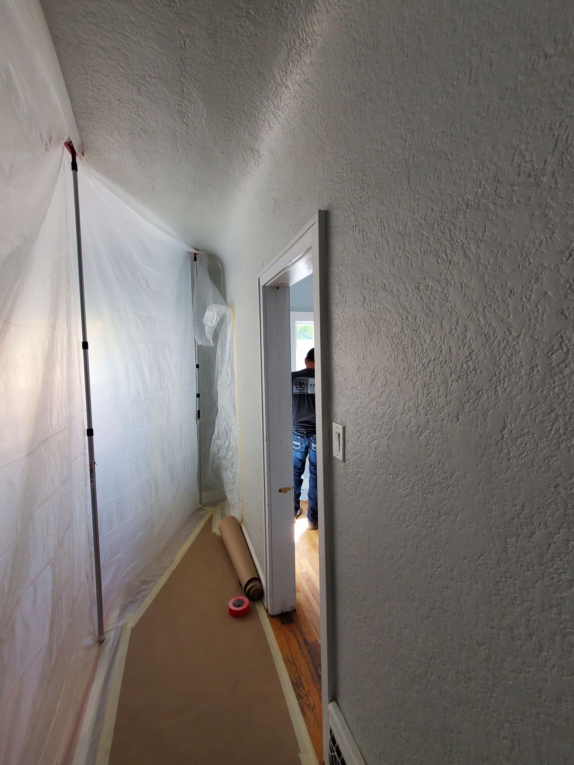 A man is standing in a hallway covered in plastic.