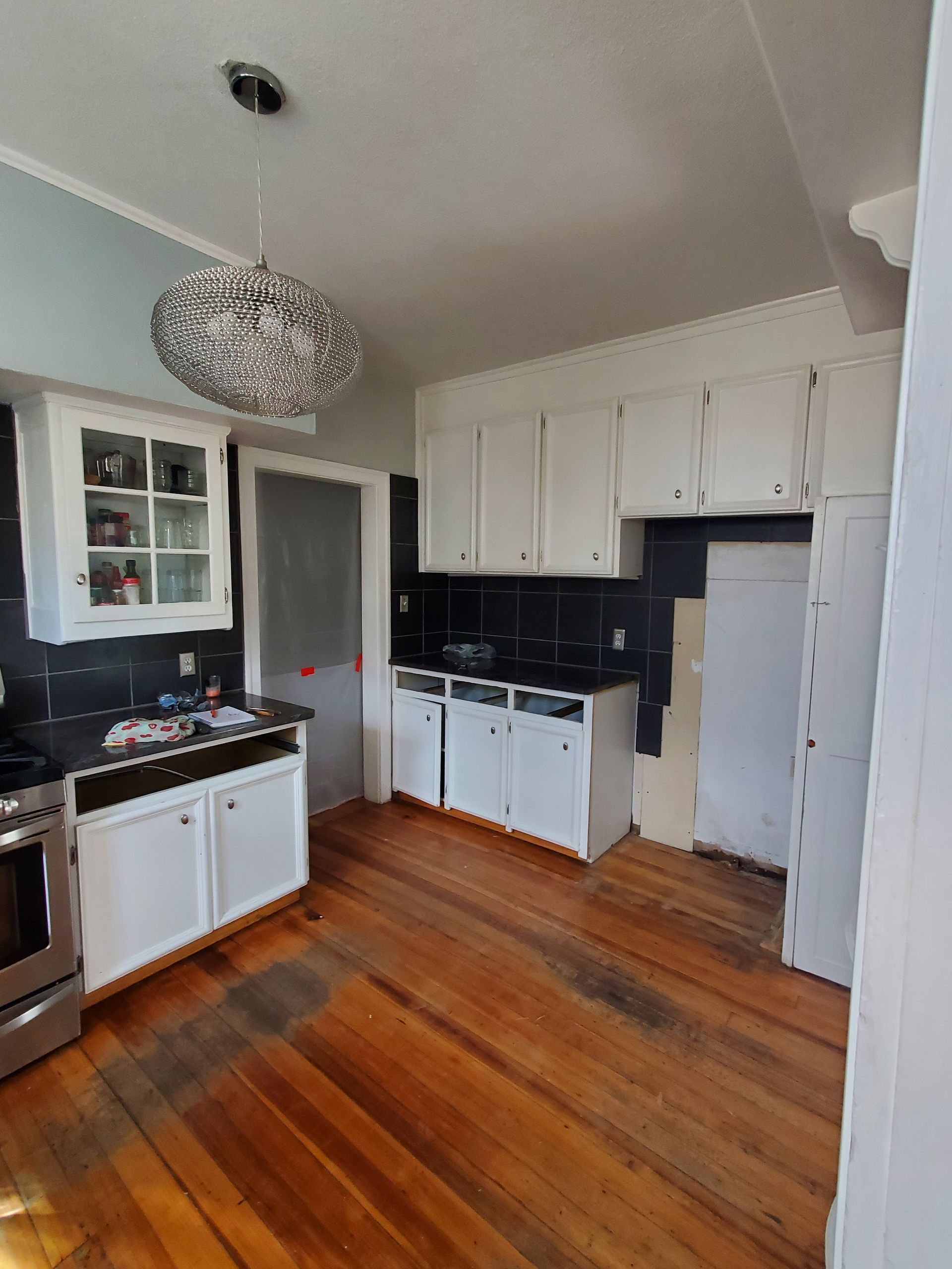 A kitchen with wooden floors and white cabinets