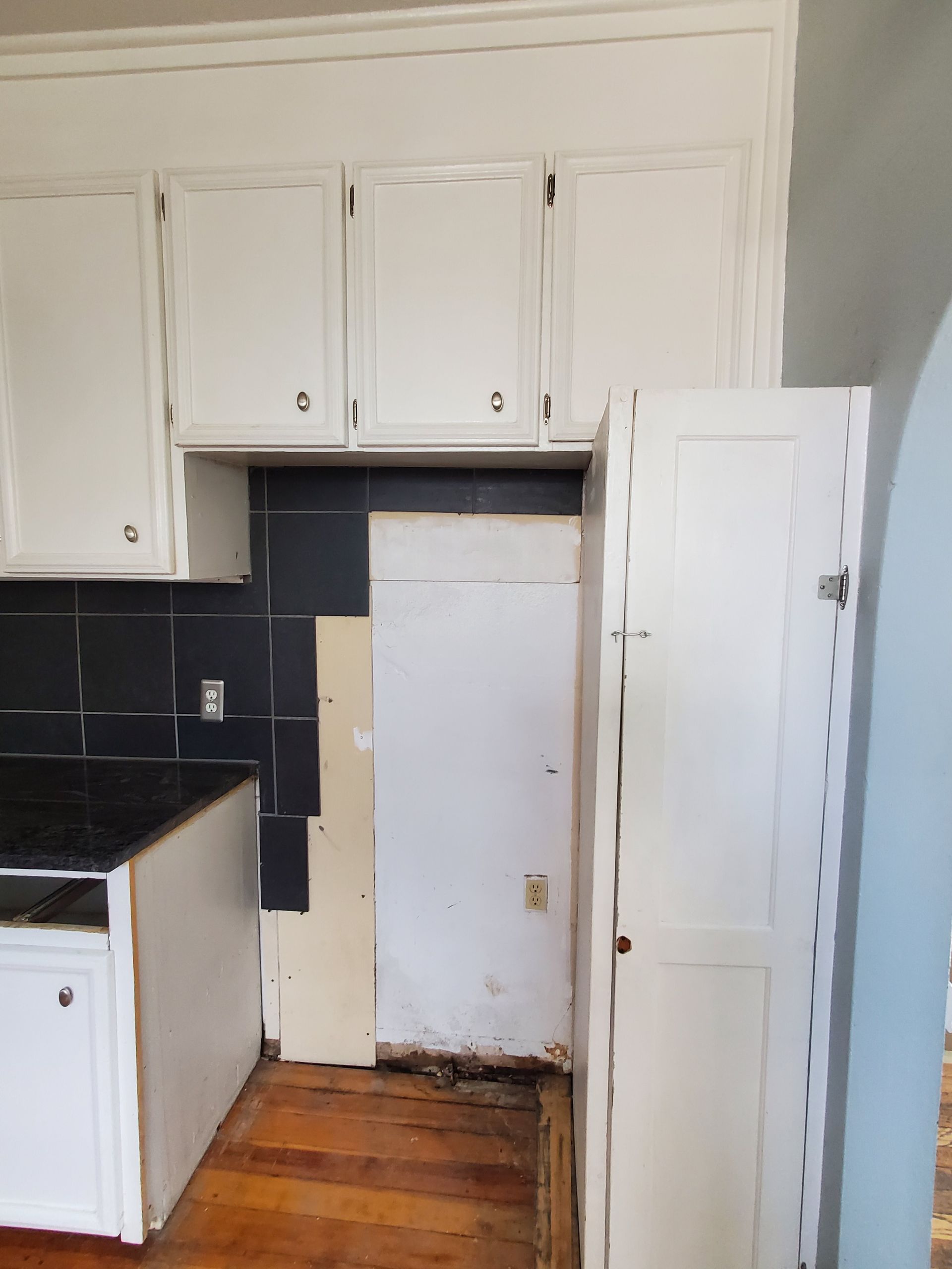 A kitchen with white cabinets and black tiles