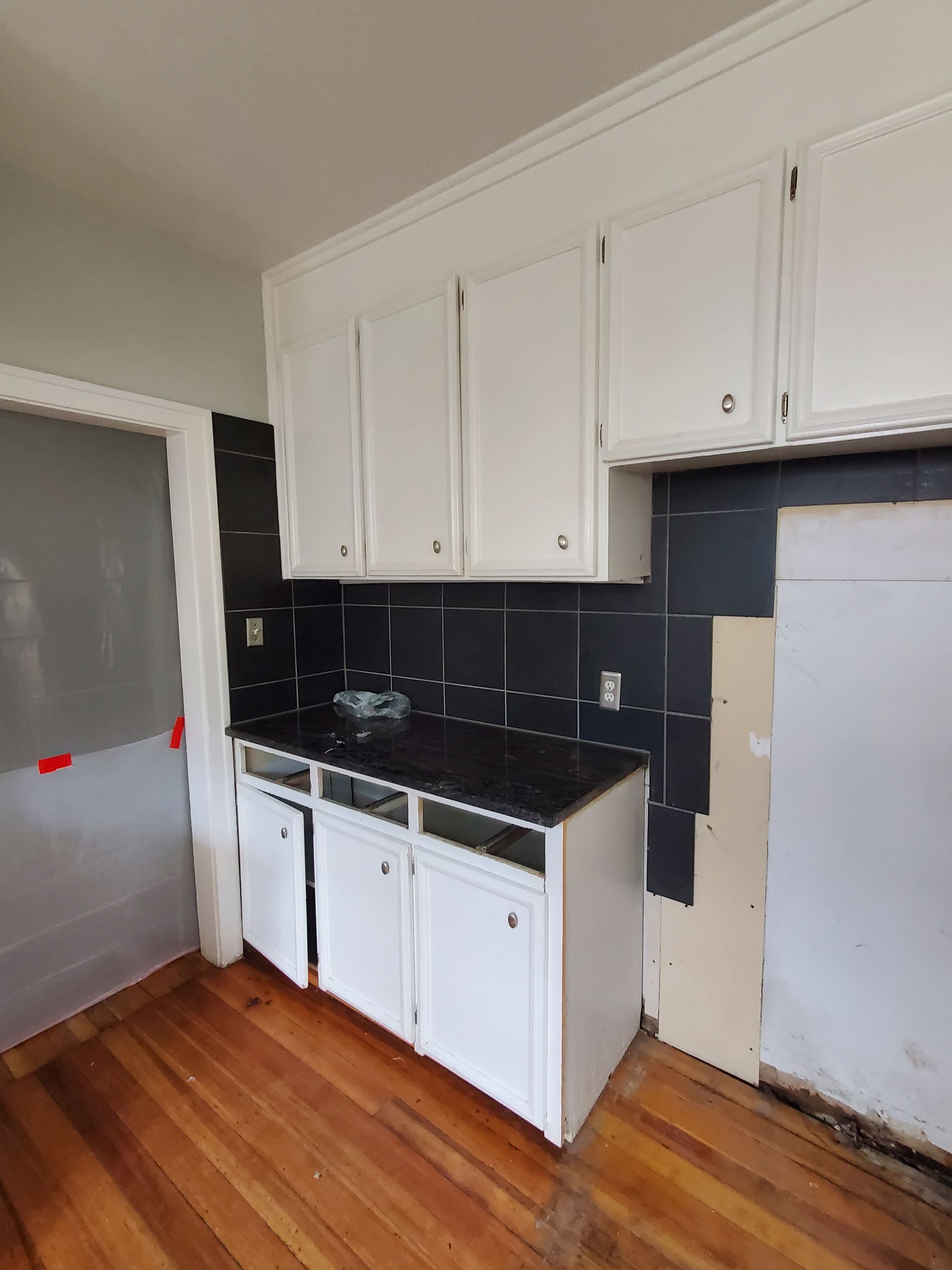 A kitchen with white cabinets and a black counter top