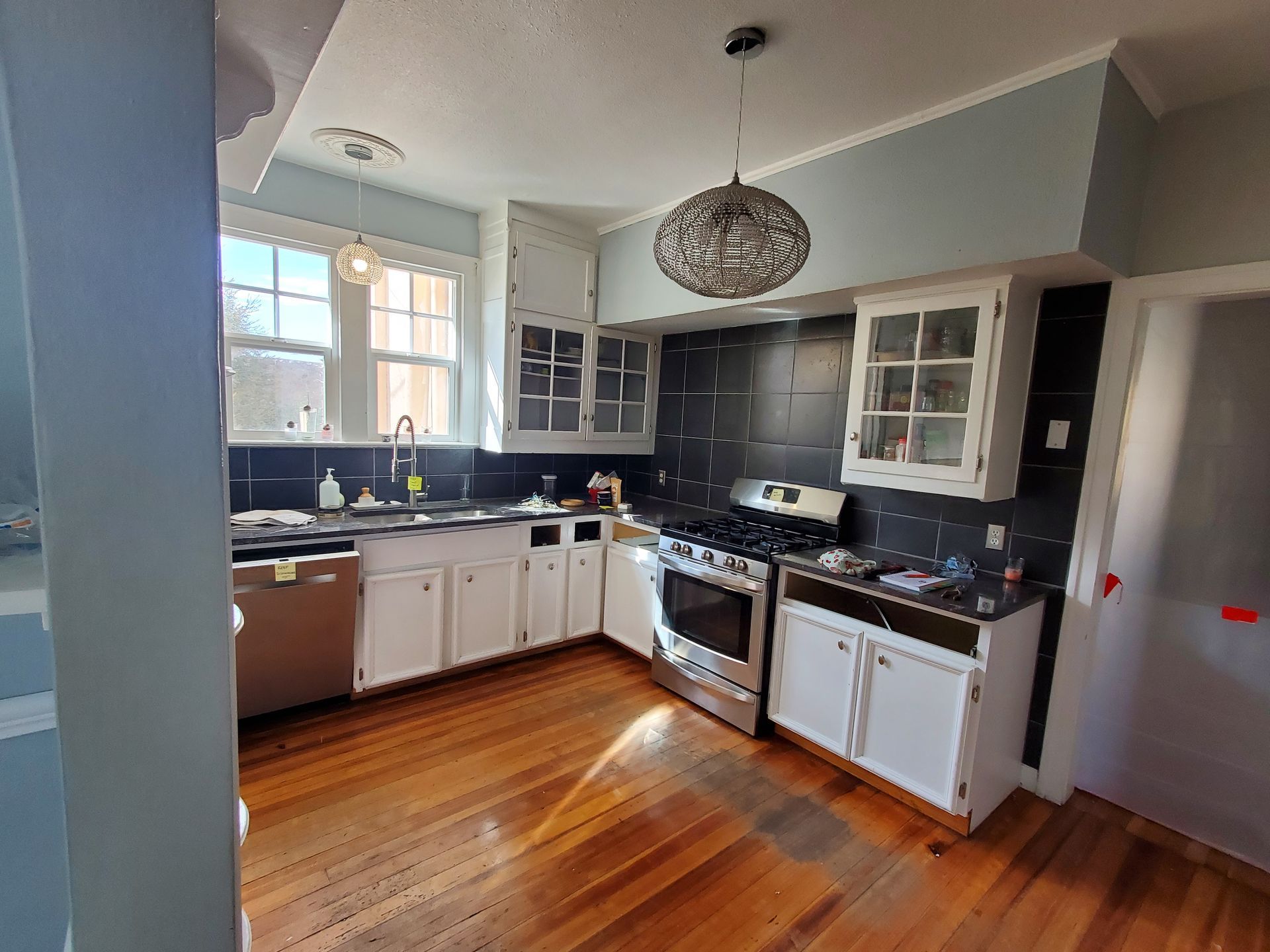 A kitchen with wooden floors and white cabinets and a stove.