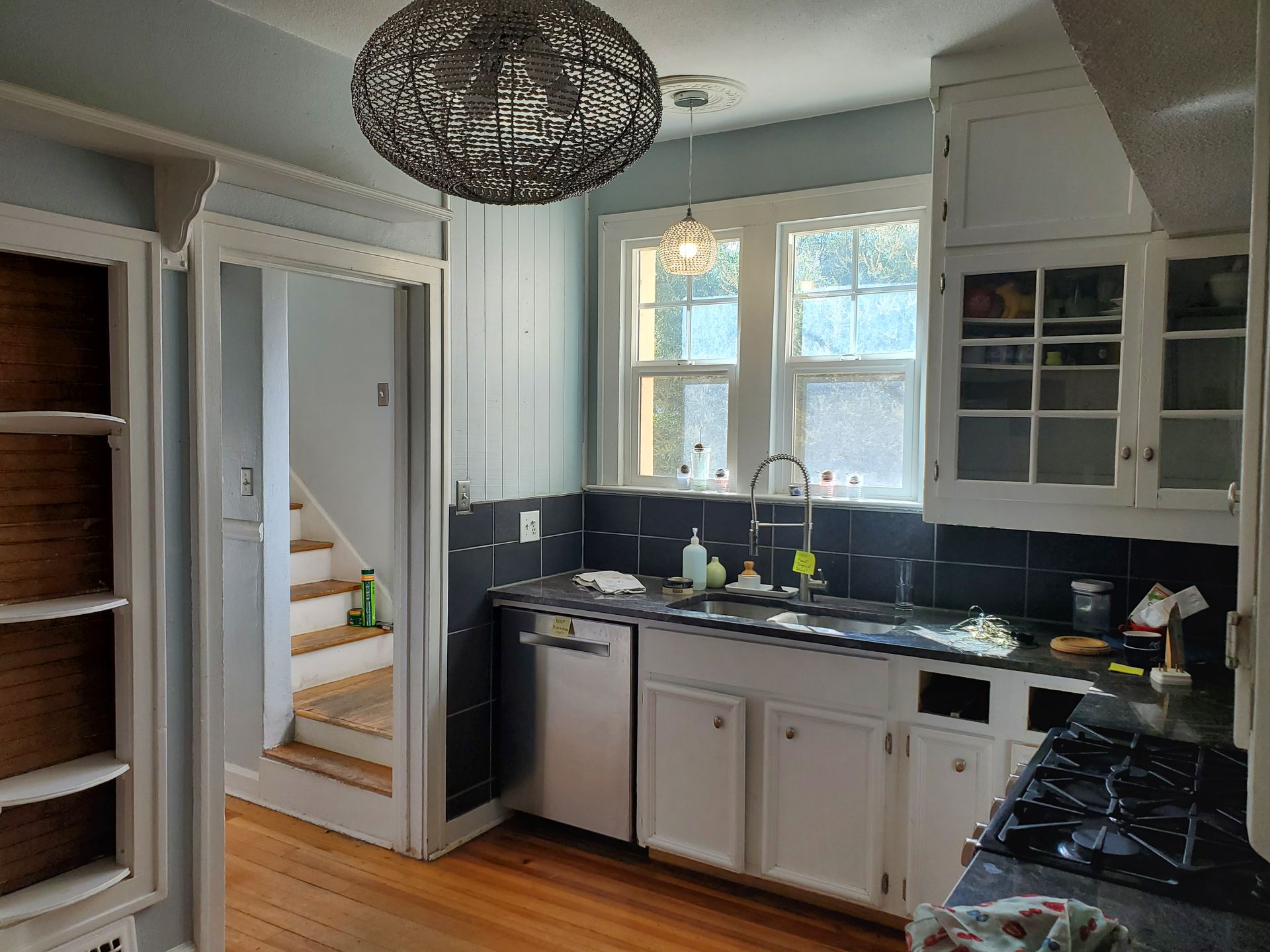 A kitchen with a sink , stove , dishwasher , and stairs.