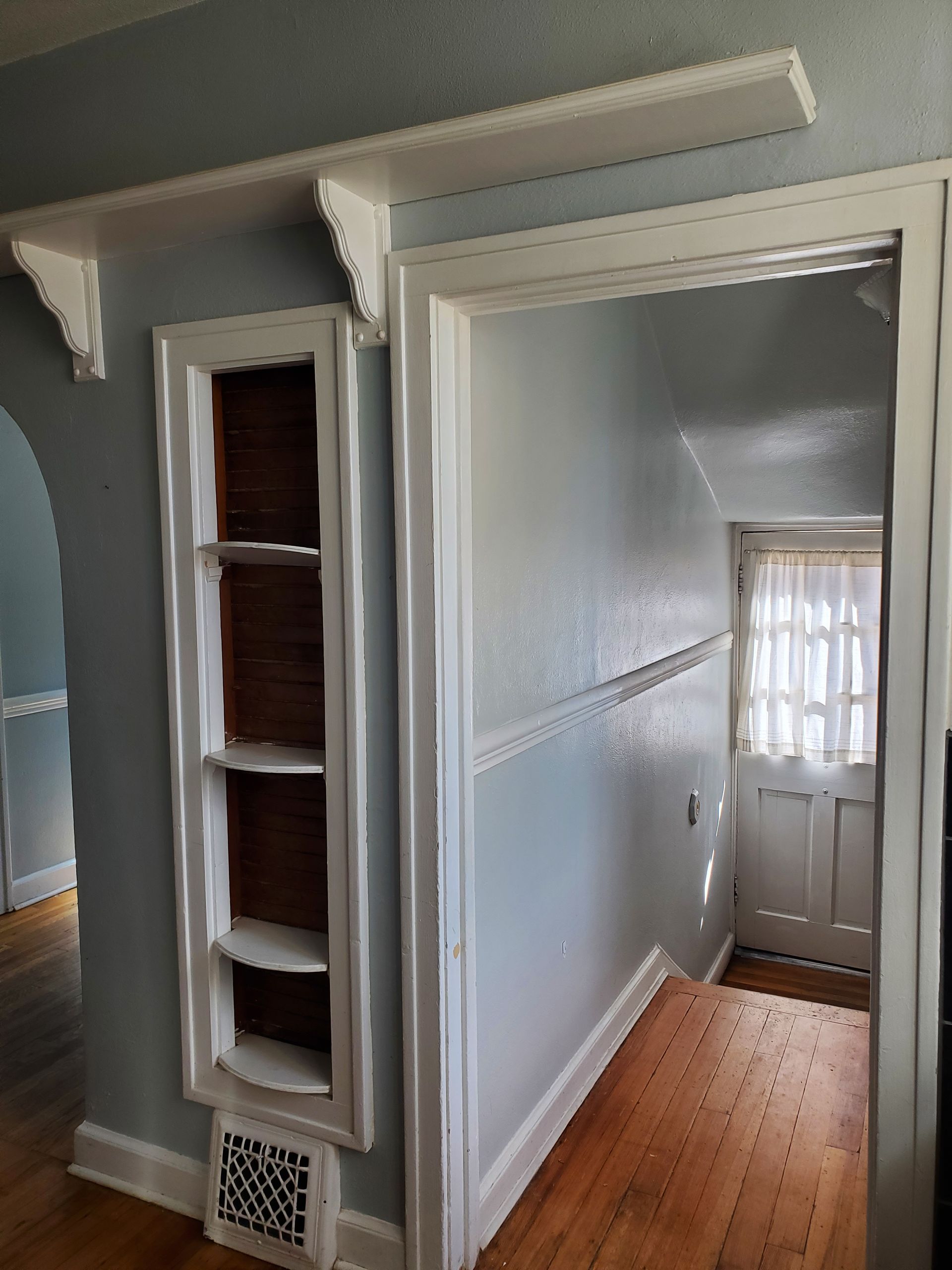 A hallway in a house with shelves and a door