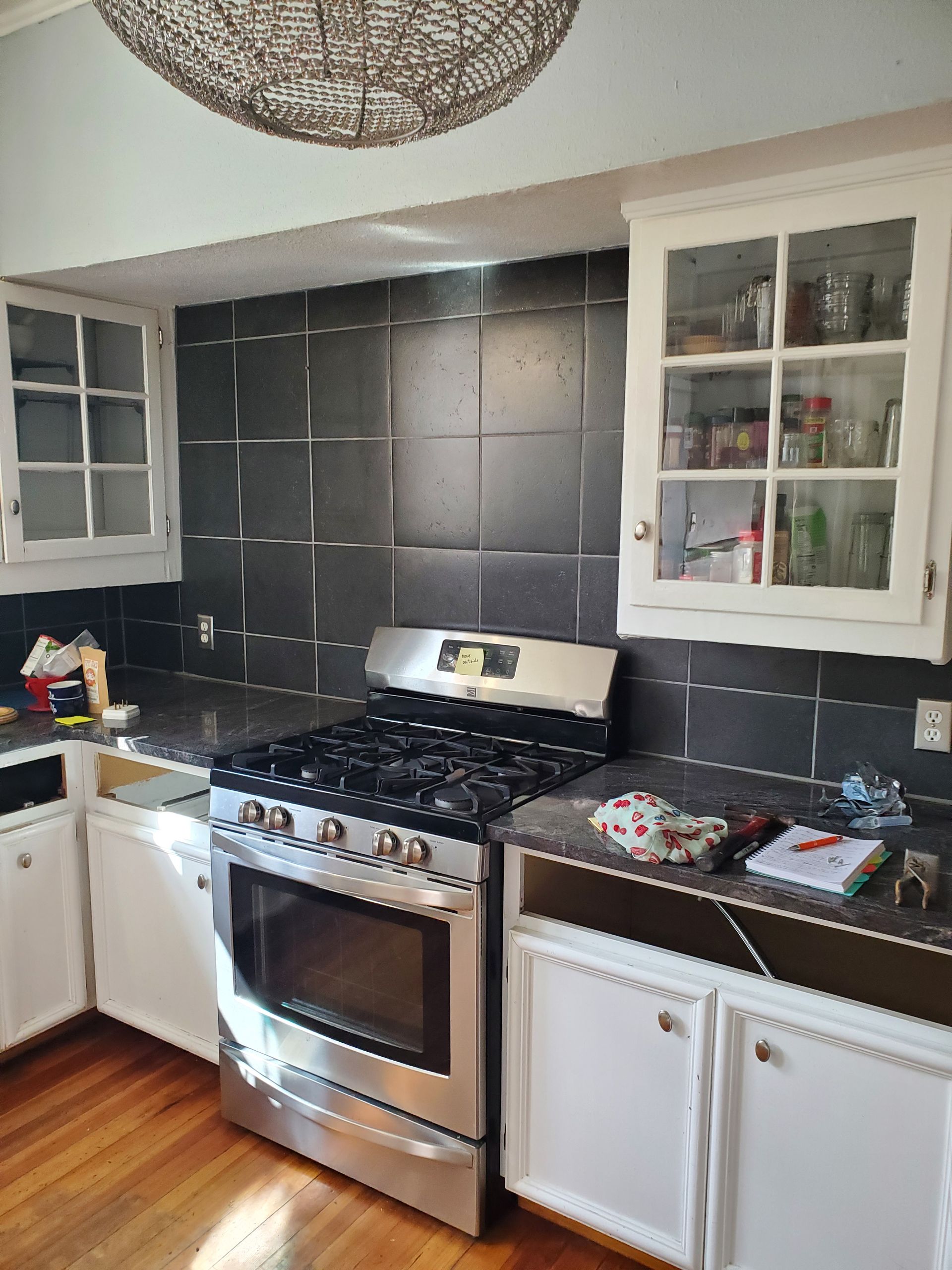 A kitchen with a stove , sink , and cabinets.