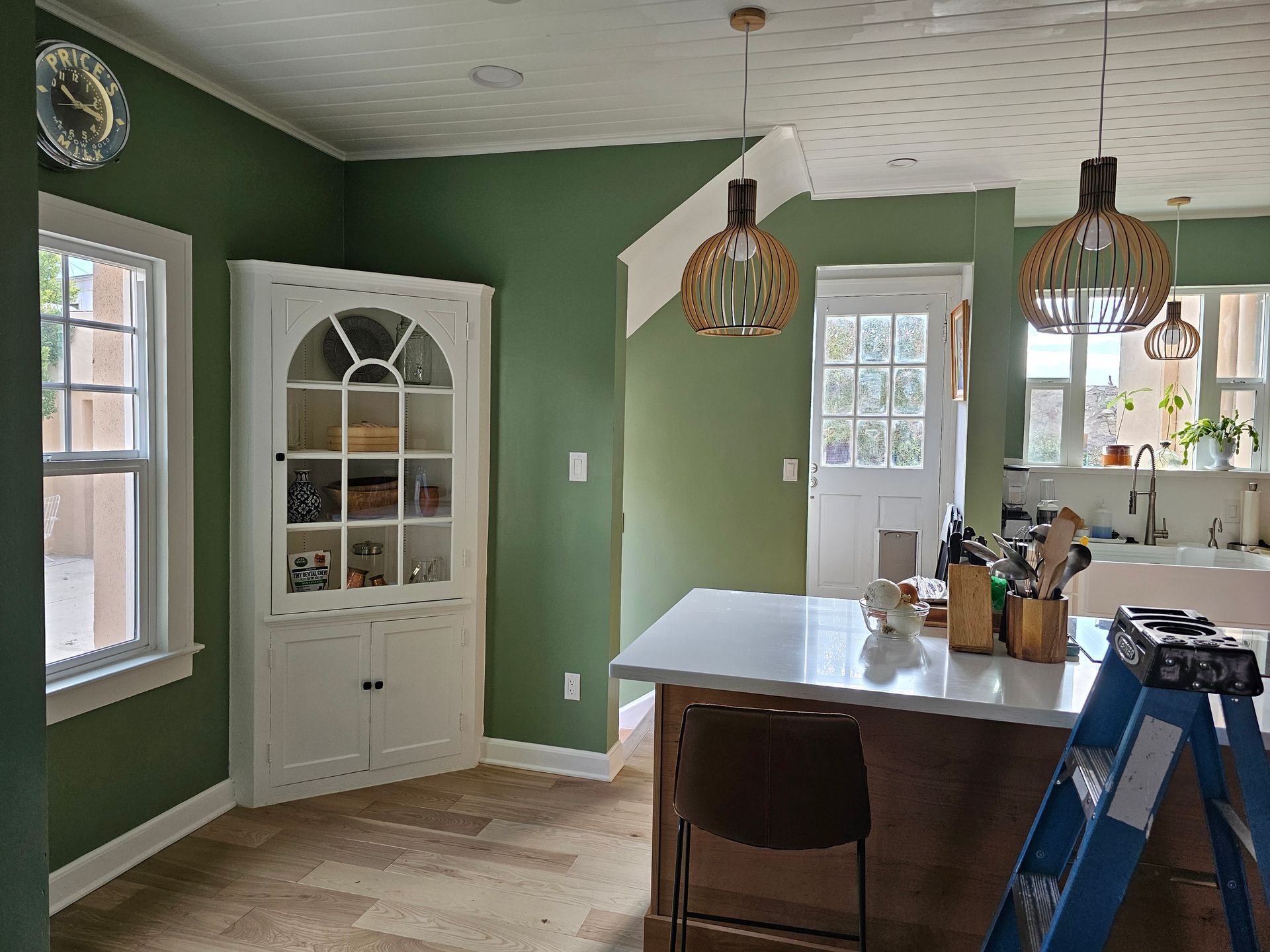 A kitchen with green walls and a ladder in the middle of the room.