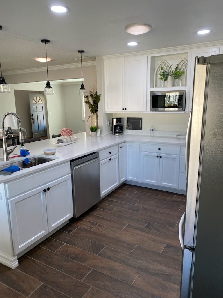 A kitchen with white cabinets , stainless steel appliances , a sink , and a refrigerator.