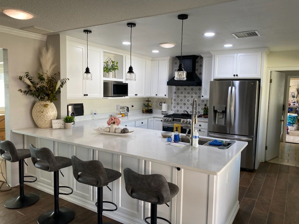 A kitchen with white cabinets , stainless steel appliances , and a large island.