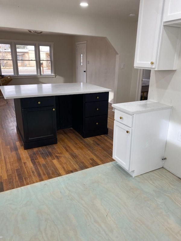 A kitchen with a black desk and white cabinets