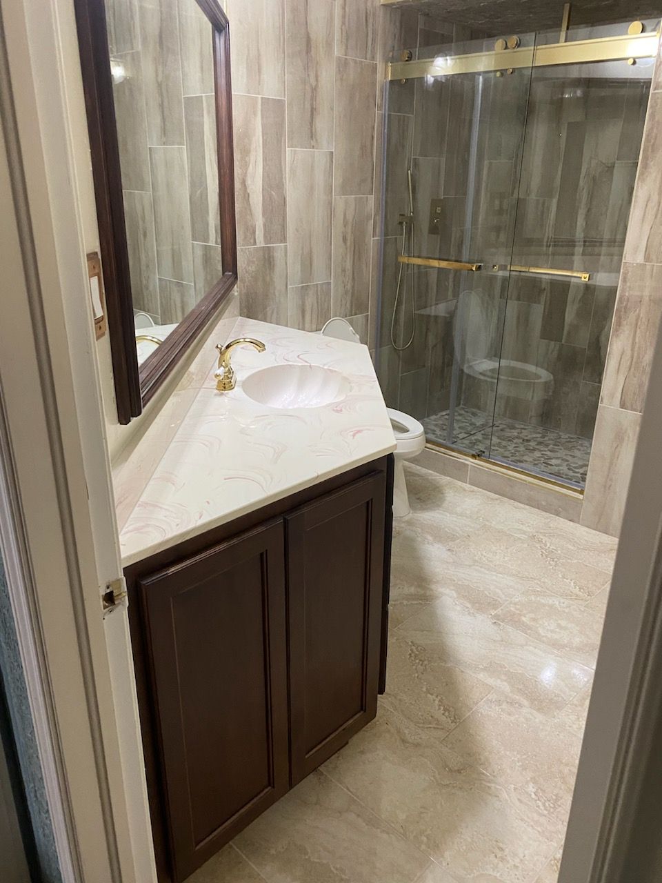 A bathroom with a sink , toilet , mirror and shower.