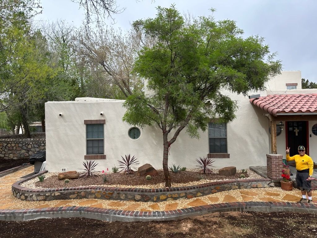 A man in a yellow shirt is standing in front of a white house.