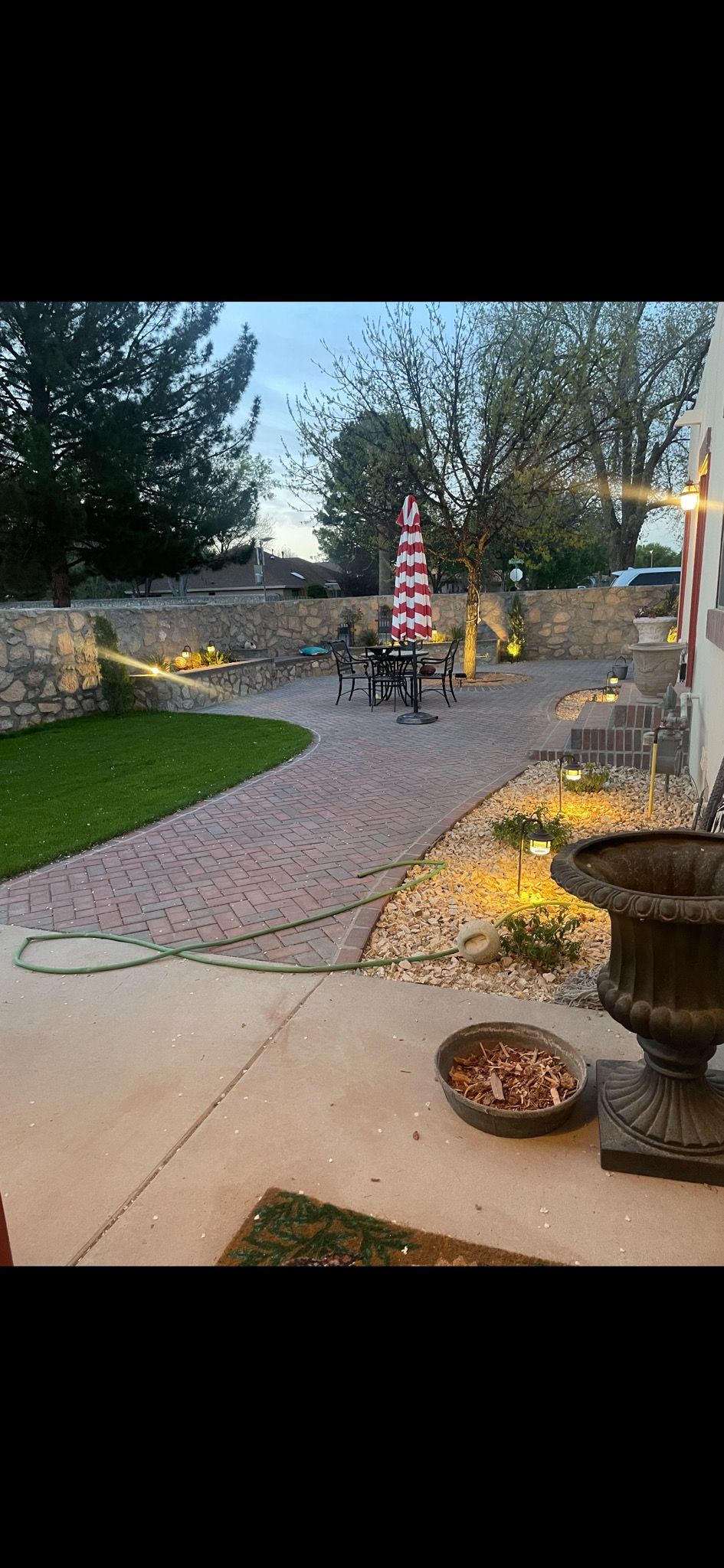 A brick walkway leading to a patio with a table and chairs.