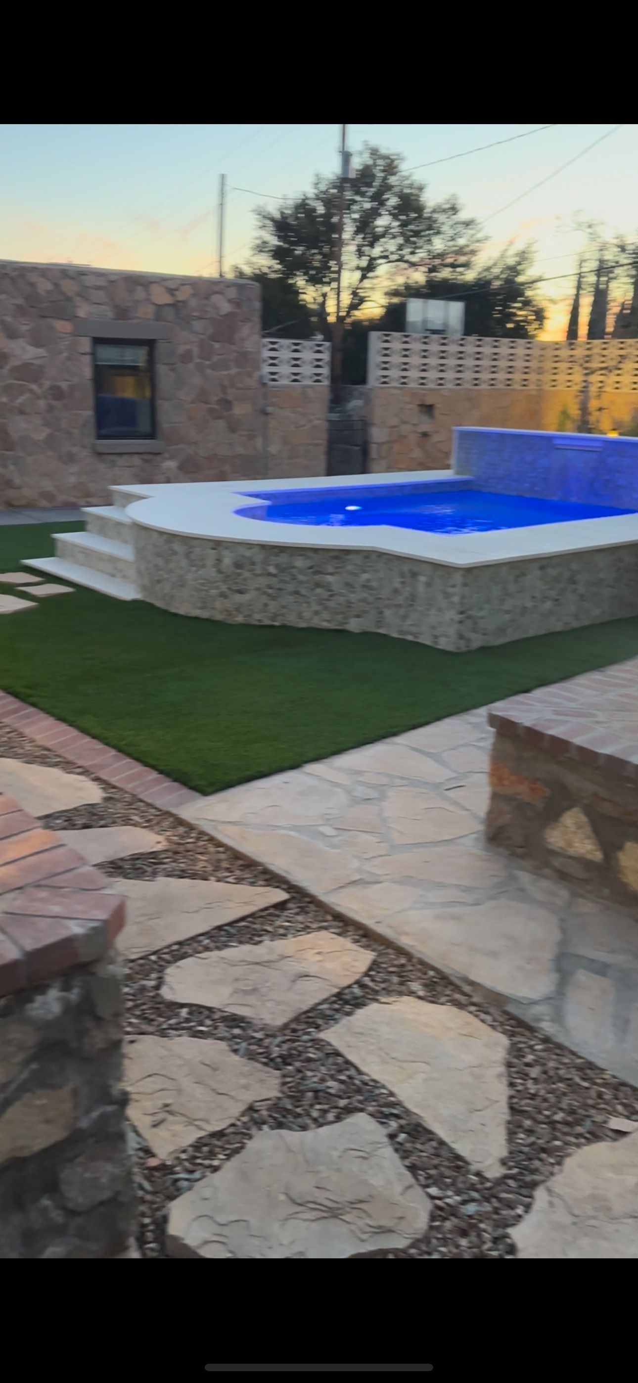 There is a large pool in the backyard of a house.