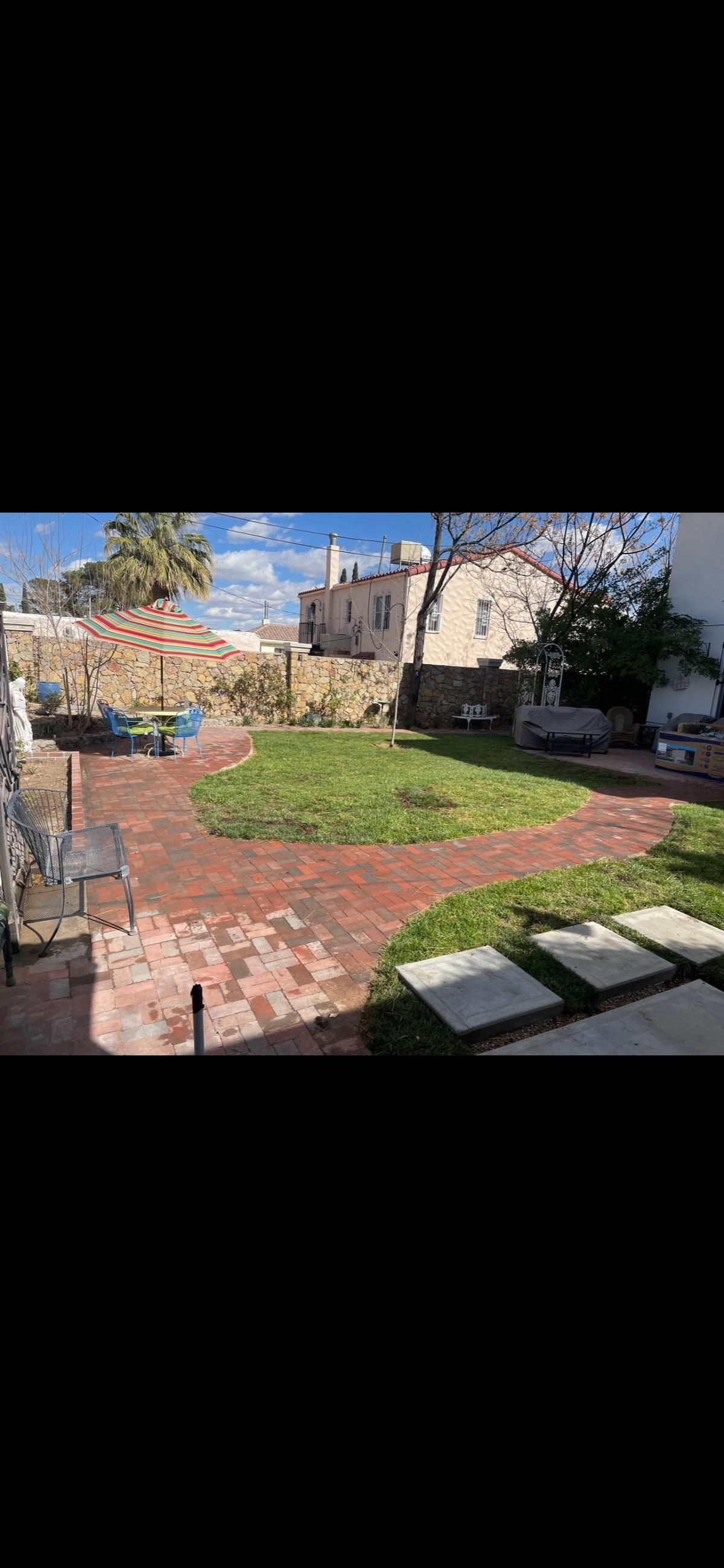 A large lawn with a brick walkway leading to a house.