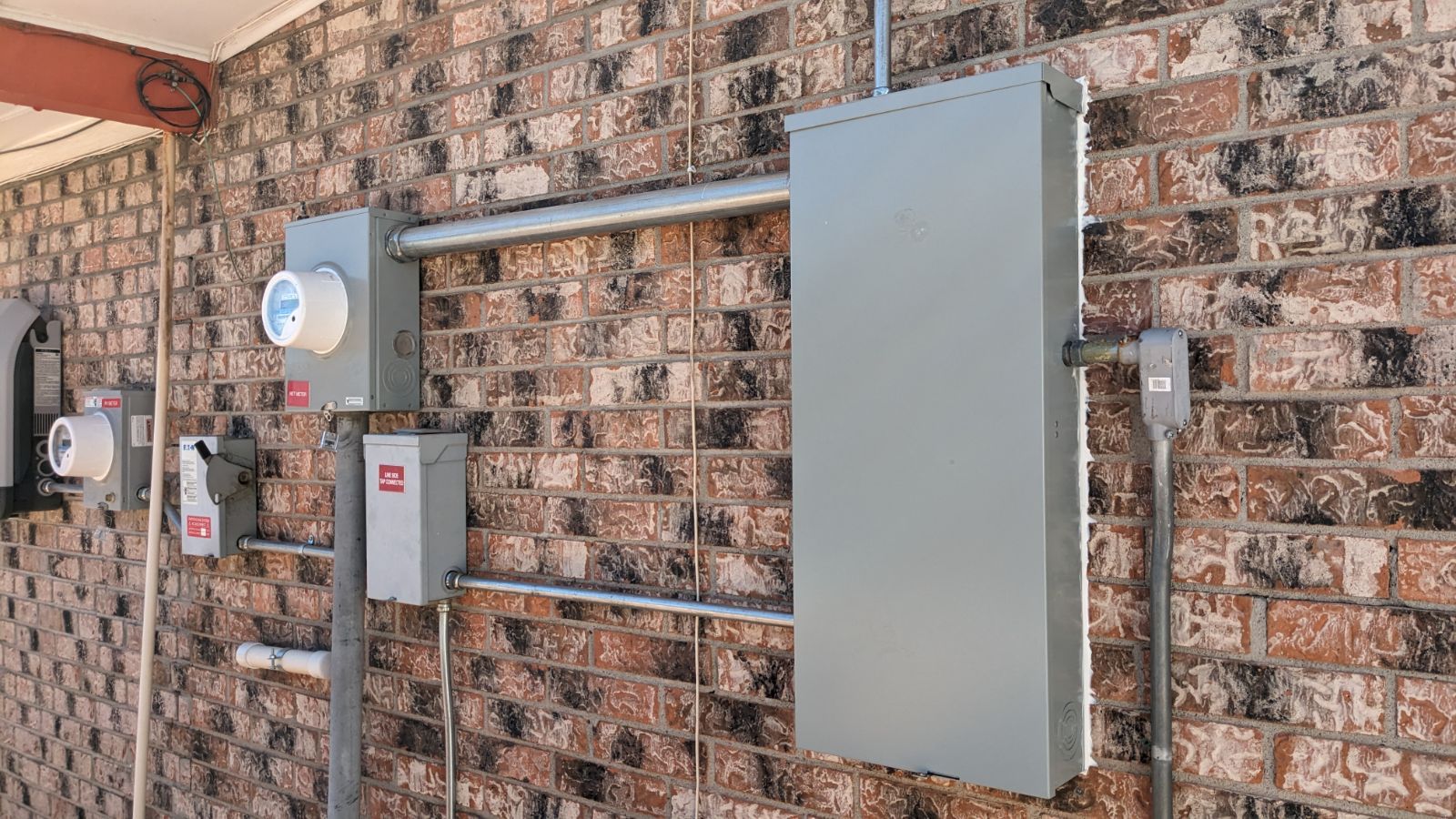 A brick wall with electrical boxes and wires on it.