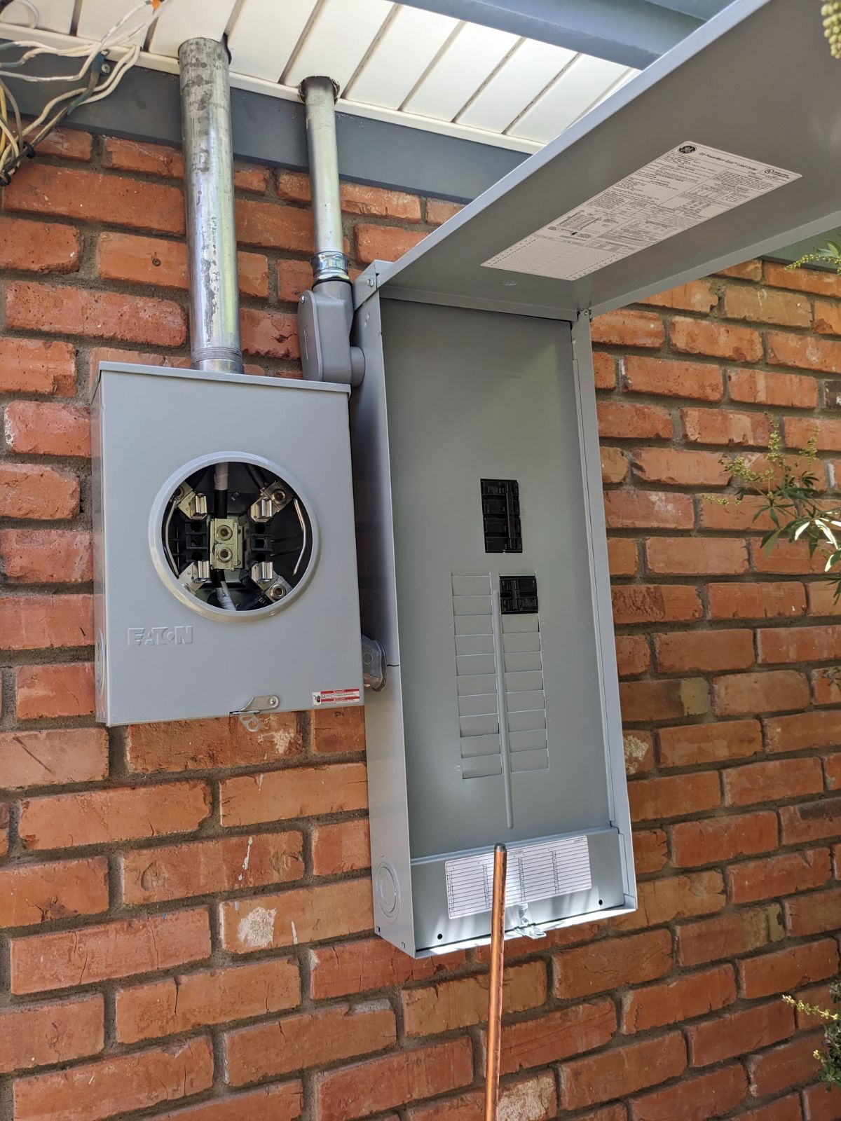 A brick wall with a electrical box attached to it.