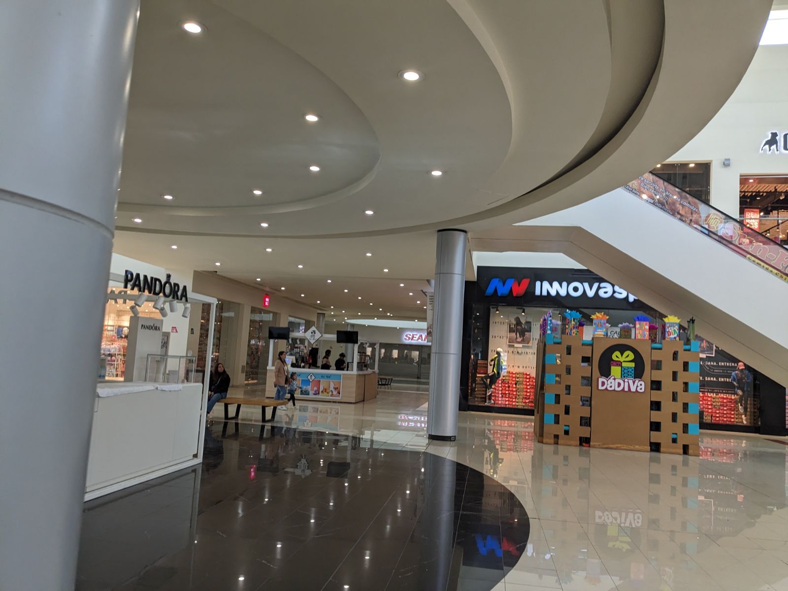 A shopping mall with a lot of shops and a circular ceiling.
