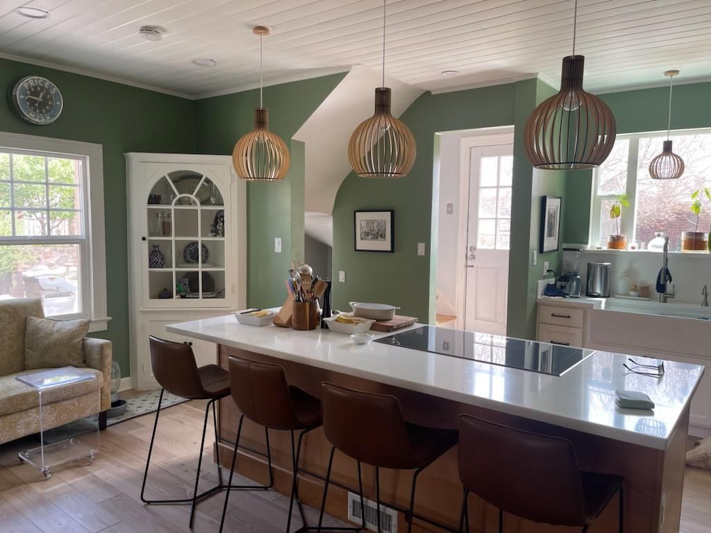 A kitchen with green walls and a large island with stools.