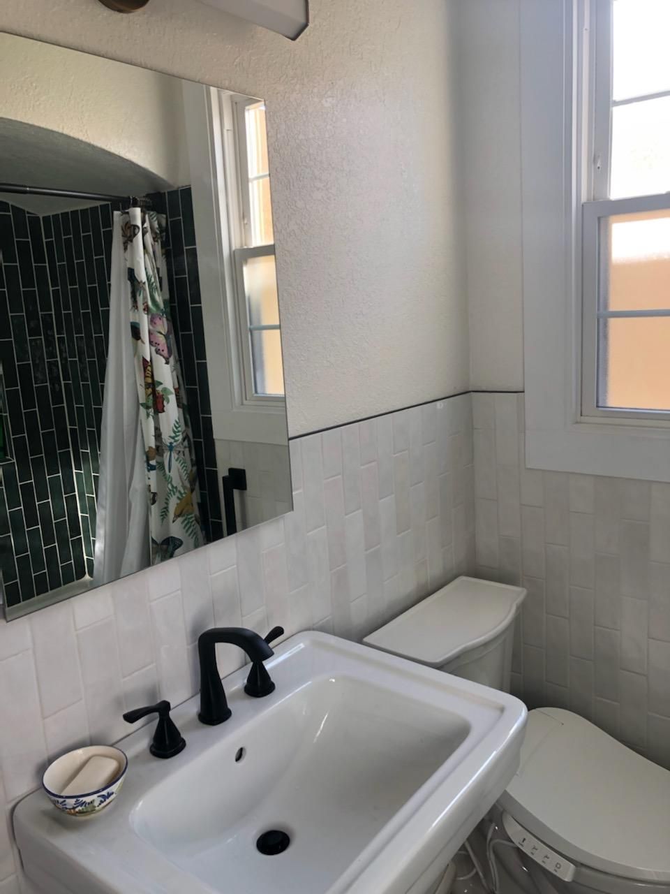 A bathroom with a sink toilet and mirror