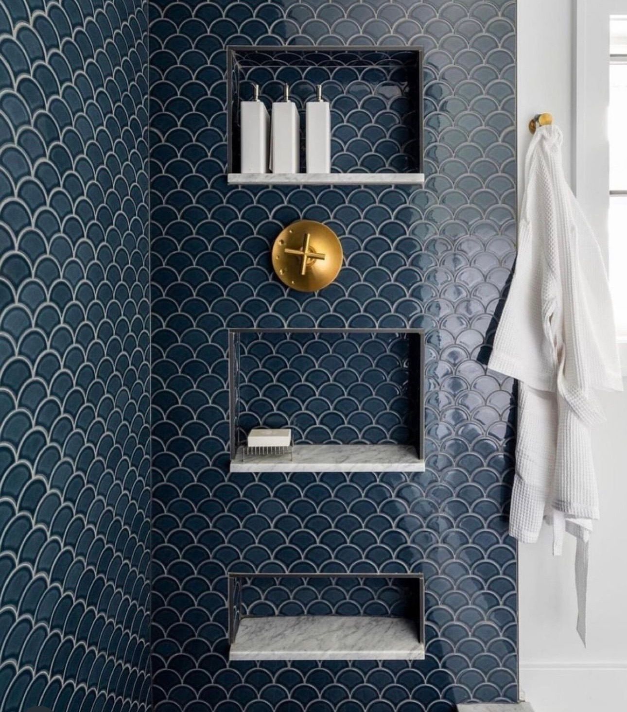 A bathroom with blue tiles and shelves in the shower.