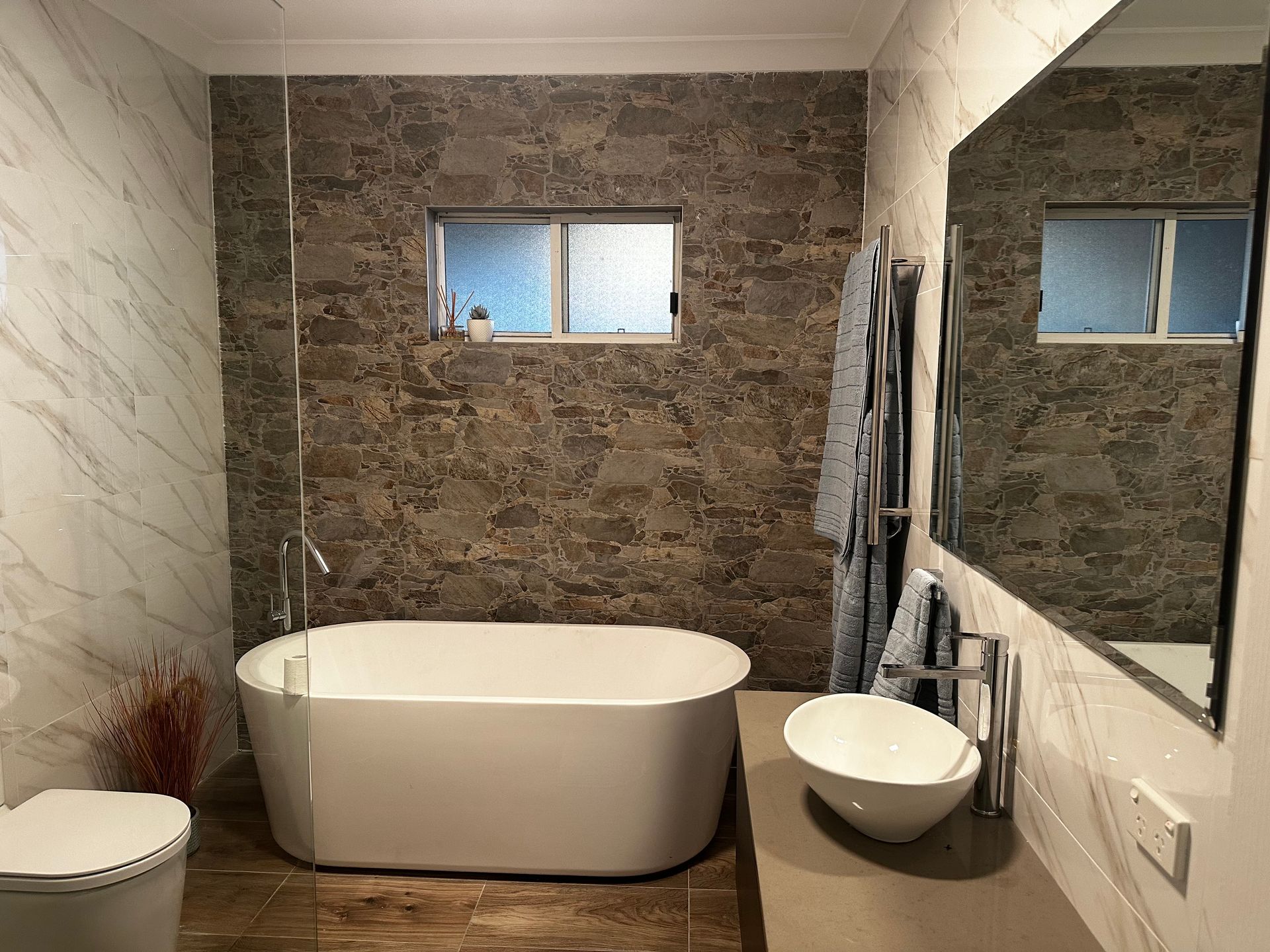 A bathroom with a bathtub , sink , toilet and mirror.