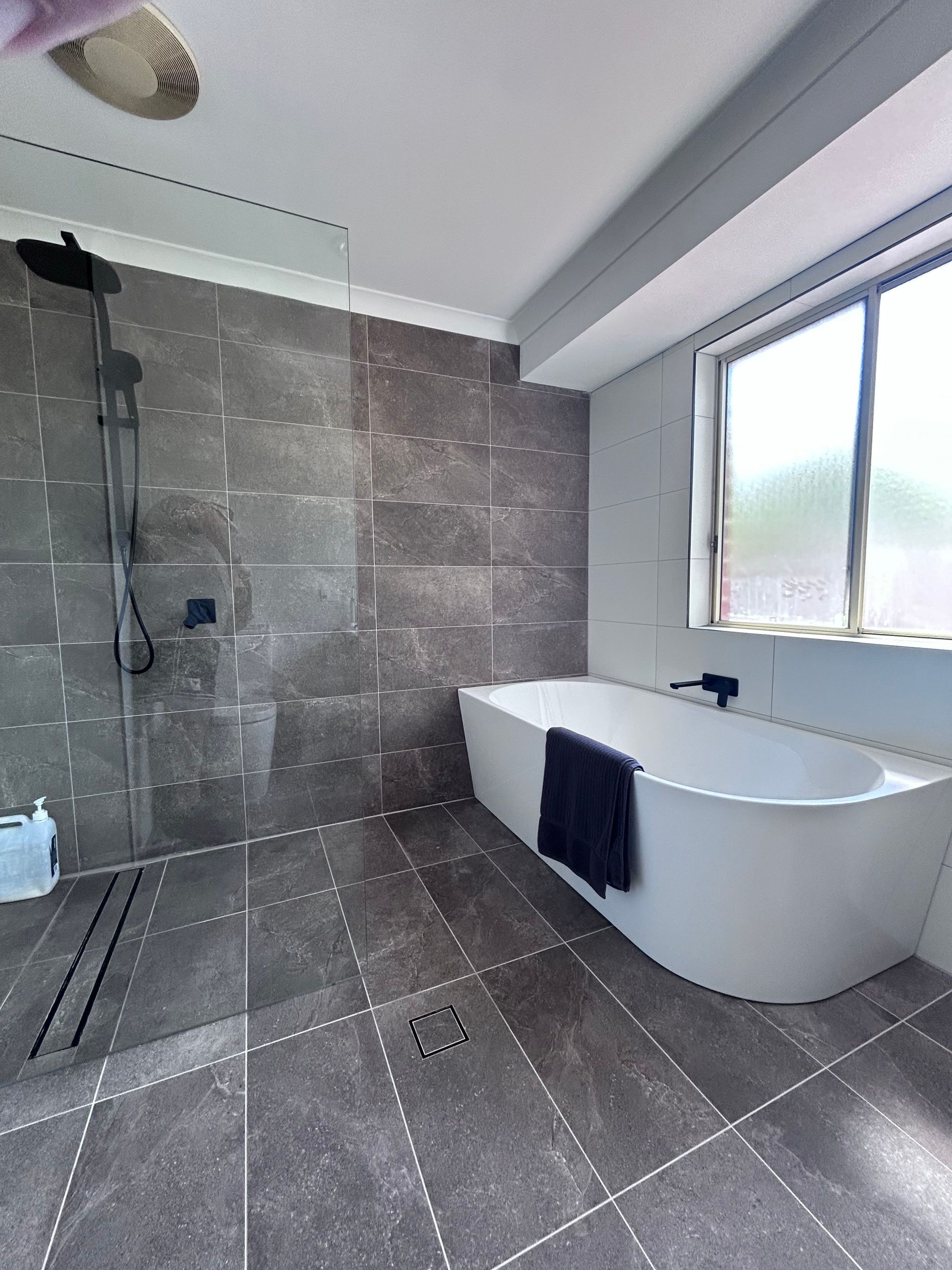 A bathroom with a bathtub , shower , and window.