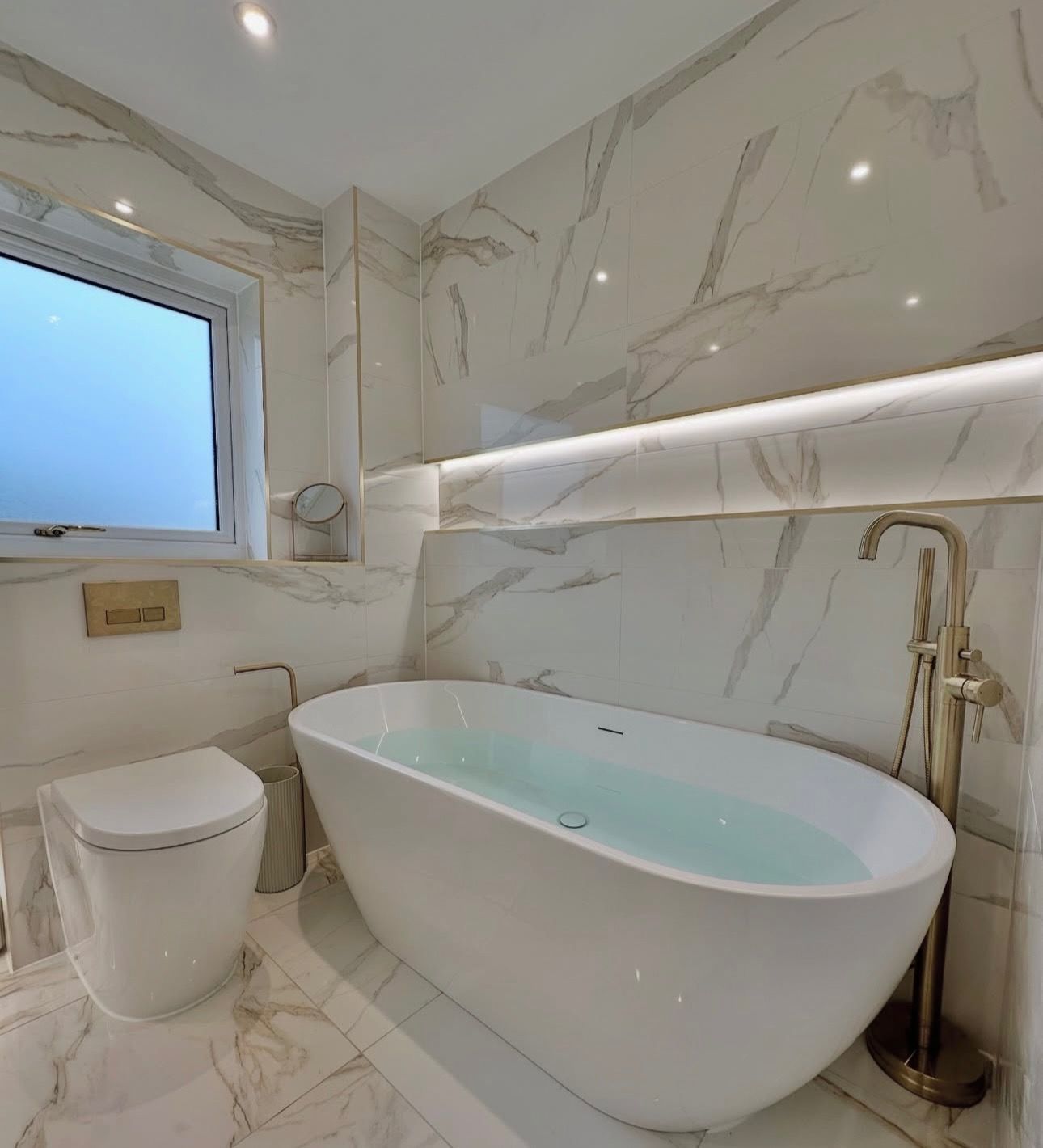 A bathroom with a bathtub , toilet and window.