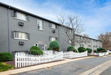 Photo of  a building showing a white picket fence surrounding some parts